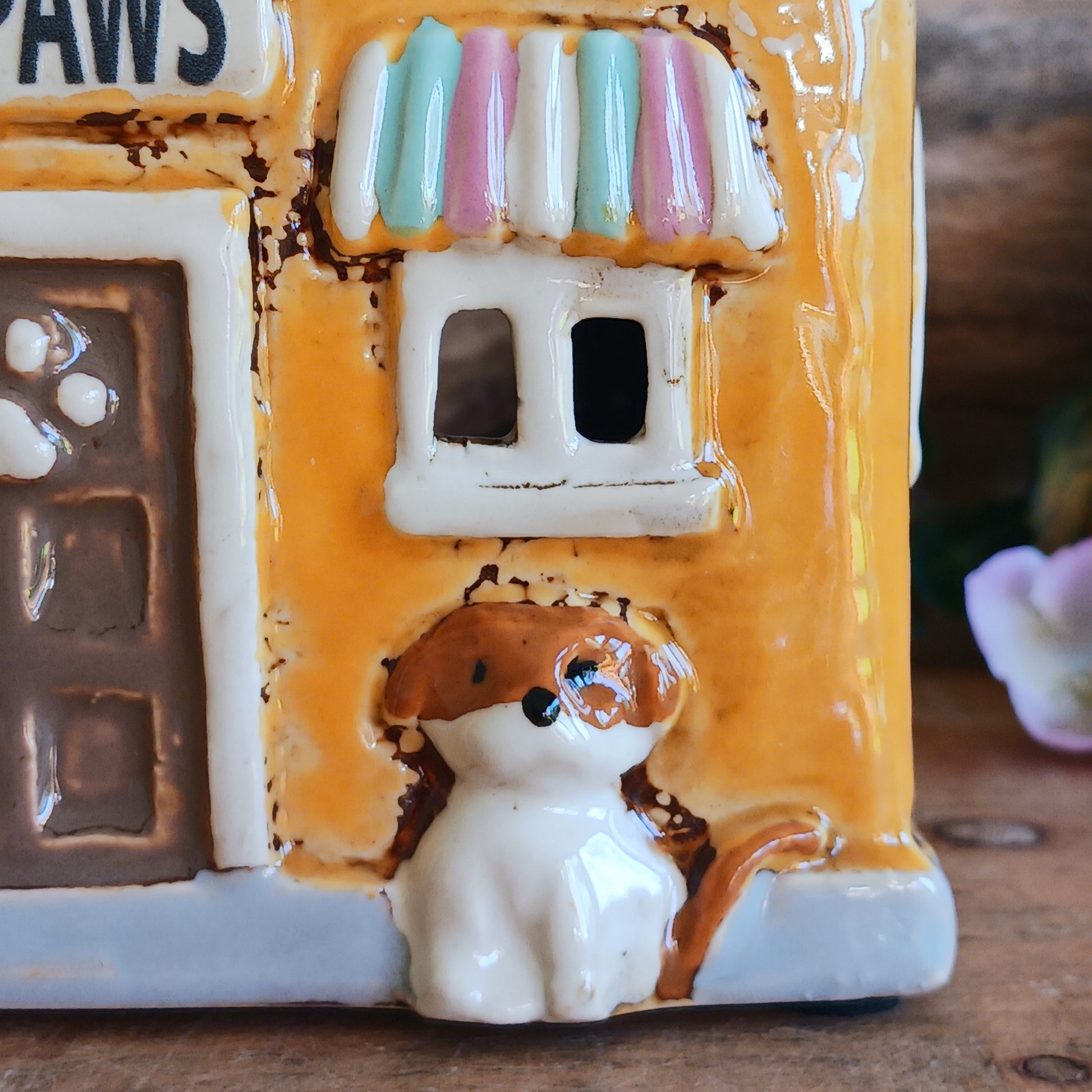 A gentle glow shines from Posh Paws, where tiny windows flicker with warmth as if welcoming beloved companions into a magical village haven. This Shudehill Village Pottery tealight house is crafted from ceramic, allowing candlelight to dance softly through its details, creating a comforting and enchanted atmosphere.