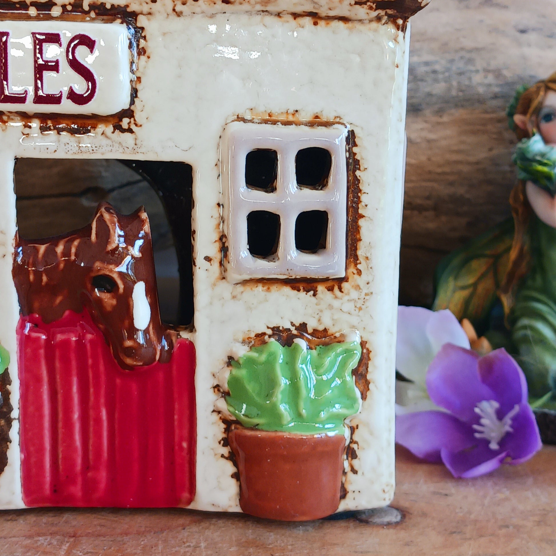 Nestled at the edge of a quiet enchanted village, The Stables tealight house by Village Pottery glows with a soft, grounding warmth. Crafted from ceramic and measuring 17x8x8cm, this rustic stable invites candlelight to flicker through its windows like a lantern for wandering spirits and kindred souls.