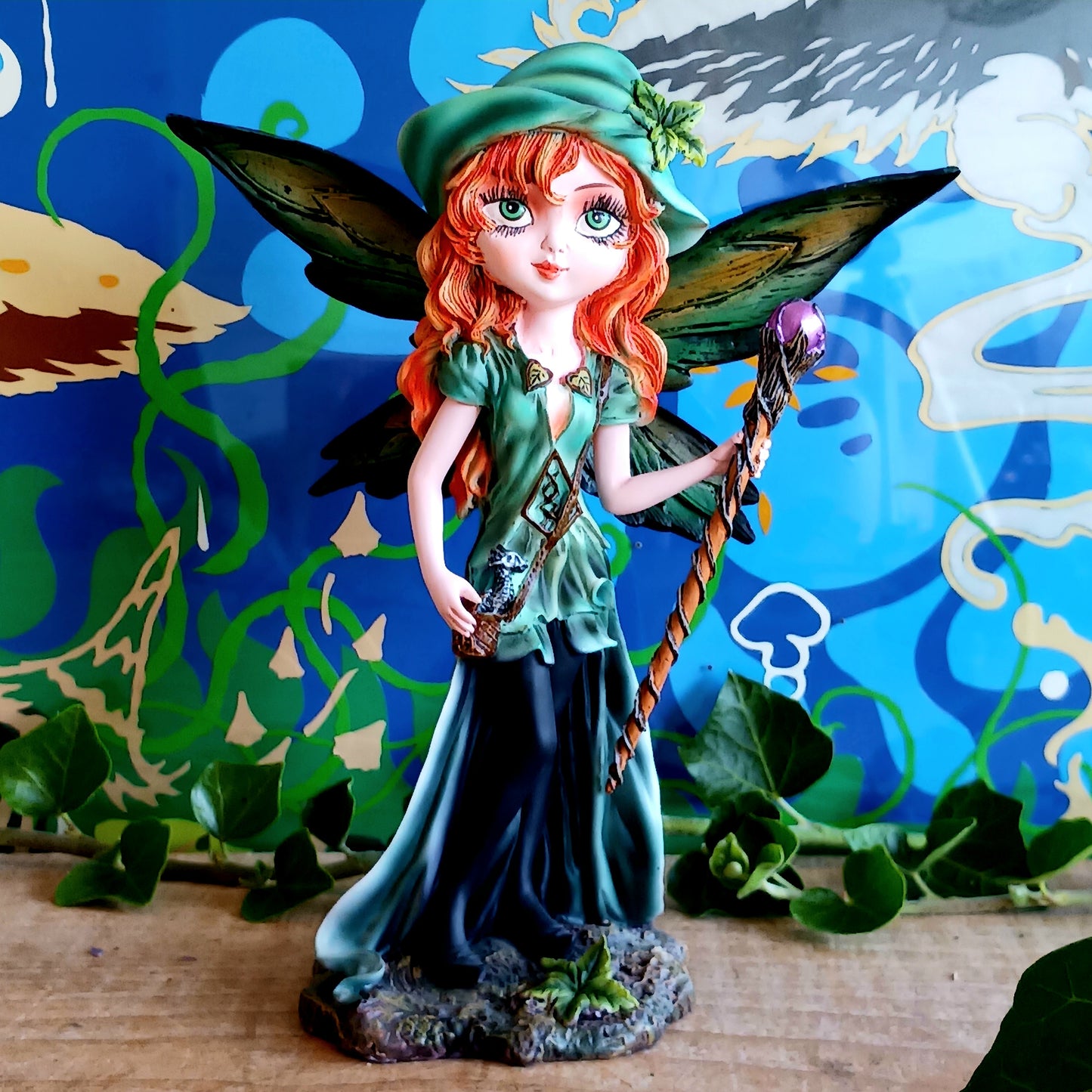 Meet Forest Fae, the whimsical guardian of the woods. This stunning standing fairy figurine captures the perfect blend of natural beauty and kawaii charm. Hand-painted with exquisite detail, she wears a lush forest green outfit, accented by leaf-shaped brooches, and holds a mystical staff crowned with a purple jewel. 
