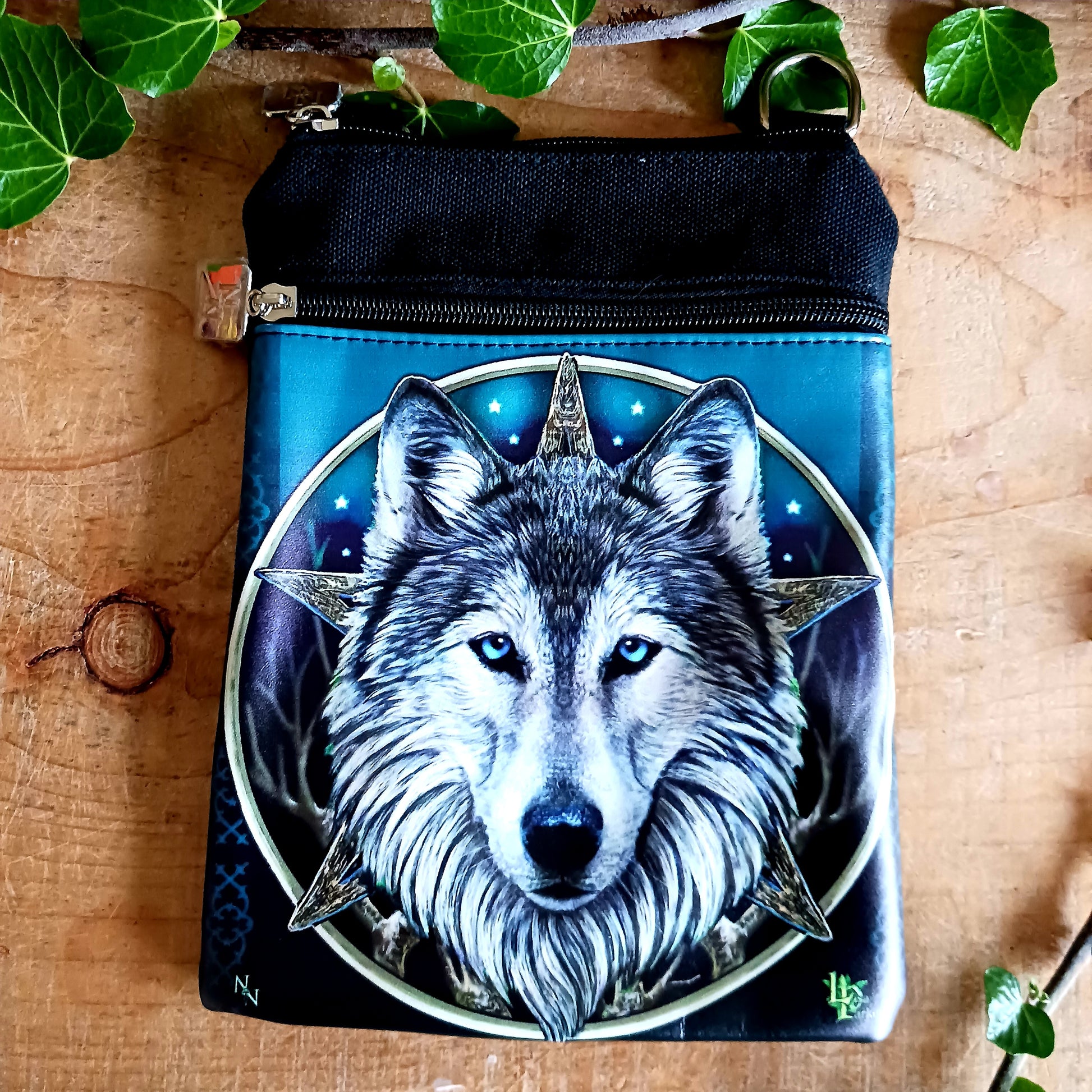 Step into the wild with this visually striking Lisa Parker Wolf Shoulder Bag, from Nemesis Now. Featuring artwork from the renowned fantasy and wildlife artist Lisa Parker, this bag captures the raw spirit of nature and mysticism.