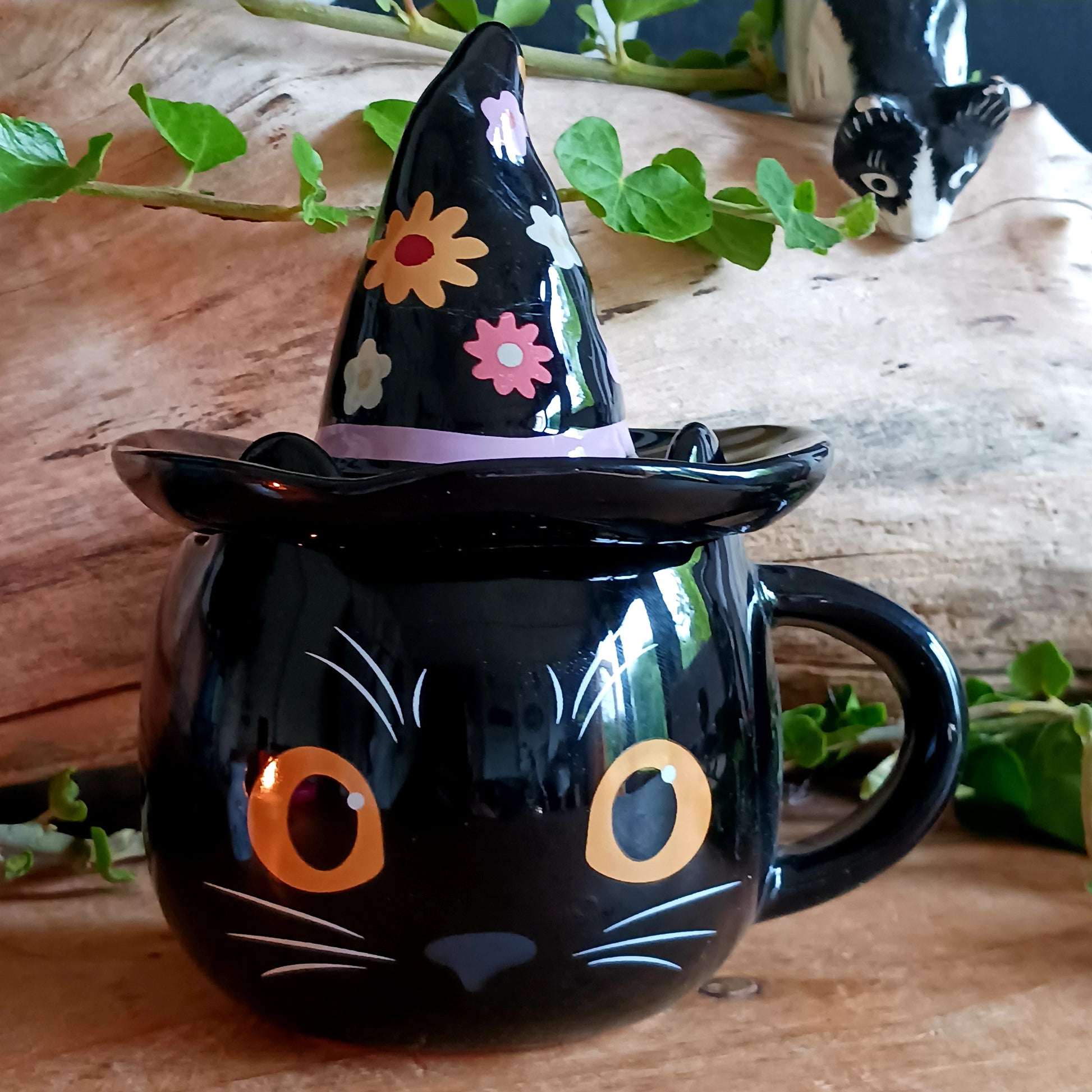 Add a spellbinding touch to your tea or coffee ritual with this groovy ceramic lidded mug, featuring an adorable cat wearing a whimsical witch hat adorned with a funky floral design. The matching ceramic lid helps keep your favourite brew warm, perfect for cosy autumn evenings or magical mornings.