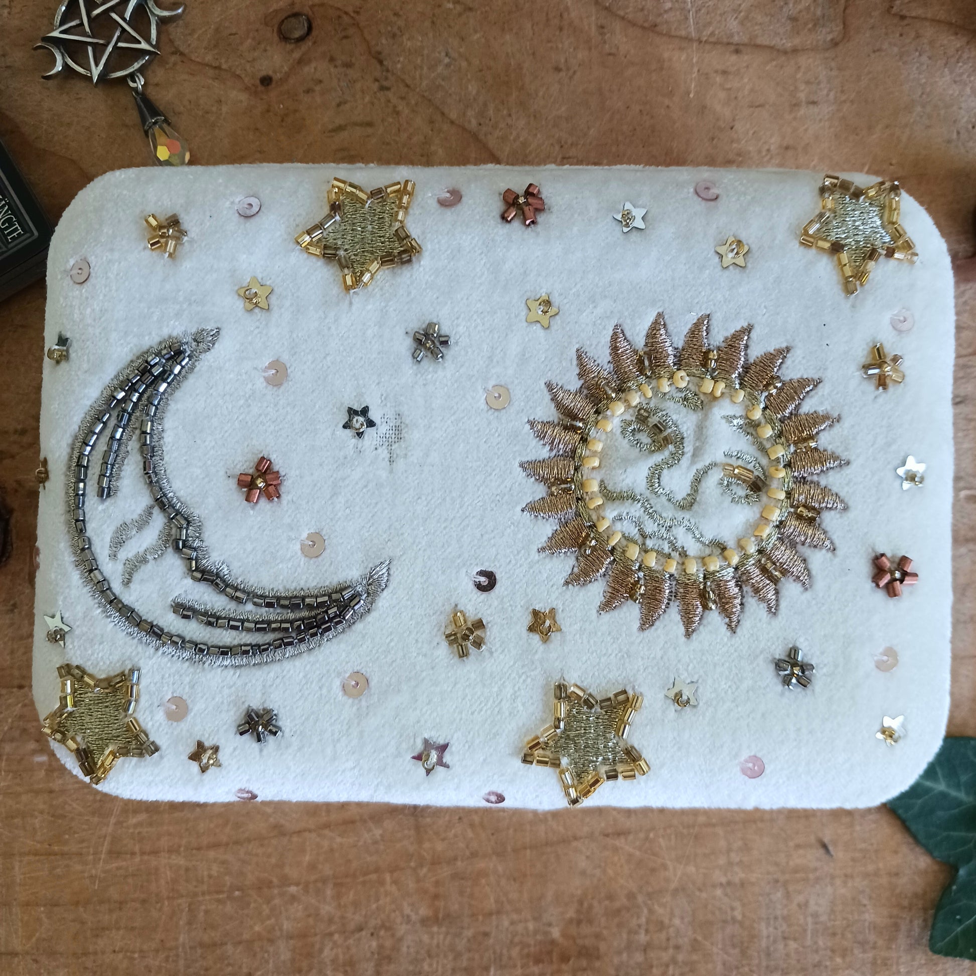 Add elegance and mystique to your collection with this finely embroidered jewellery and tarot box. Made in India and crafted from soft velvet in white, this piece is adorned with intricate embroidery and golden ornamental beads for a touch of luxury. Perfect for storing jewellery, tarot cards, crystals, or other cherished items, its small strap and button closure keep your treasures secure.