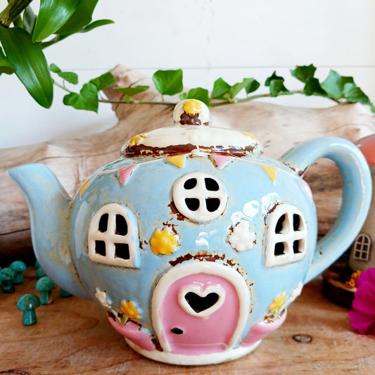 Create a warm and cosy atmosphere in your home with this charming Round Teapot Tealight Holder from the Village Pottery Collection. Crafted in a unique teapot shape, this ceramic tealight holder makes a delightful decorative piece for shelves, windowsills, or side tables. Simply place a tealight inside to enjoy a soft, glowing ambience.