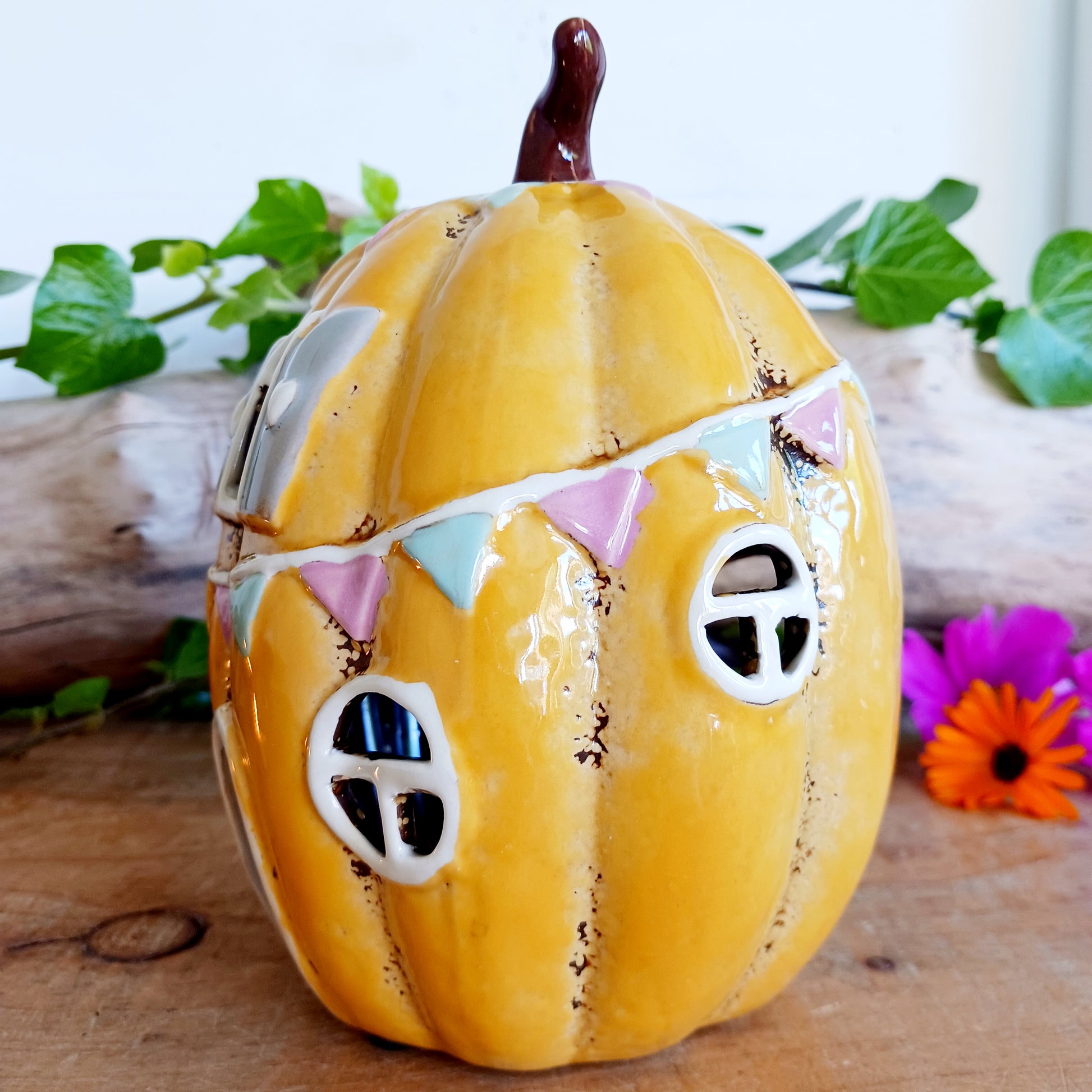 Invite a little woodland wonder into your home with the Village Pottery Pumpkin House Tealight Holder, a delightful hand-painted creation in a soft yellow ceramic glaze. Measuring 17 x 13 x 11 cm, this fairy-tale pumpkin cottage glows beautifully when lit, filling your space with warmth, light, and a touch of enchantment.