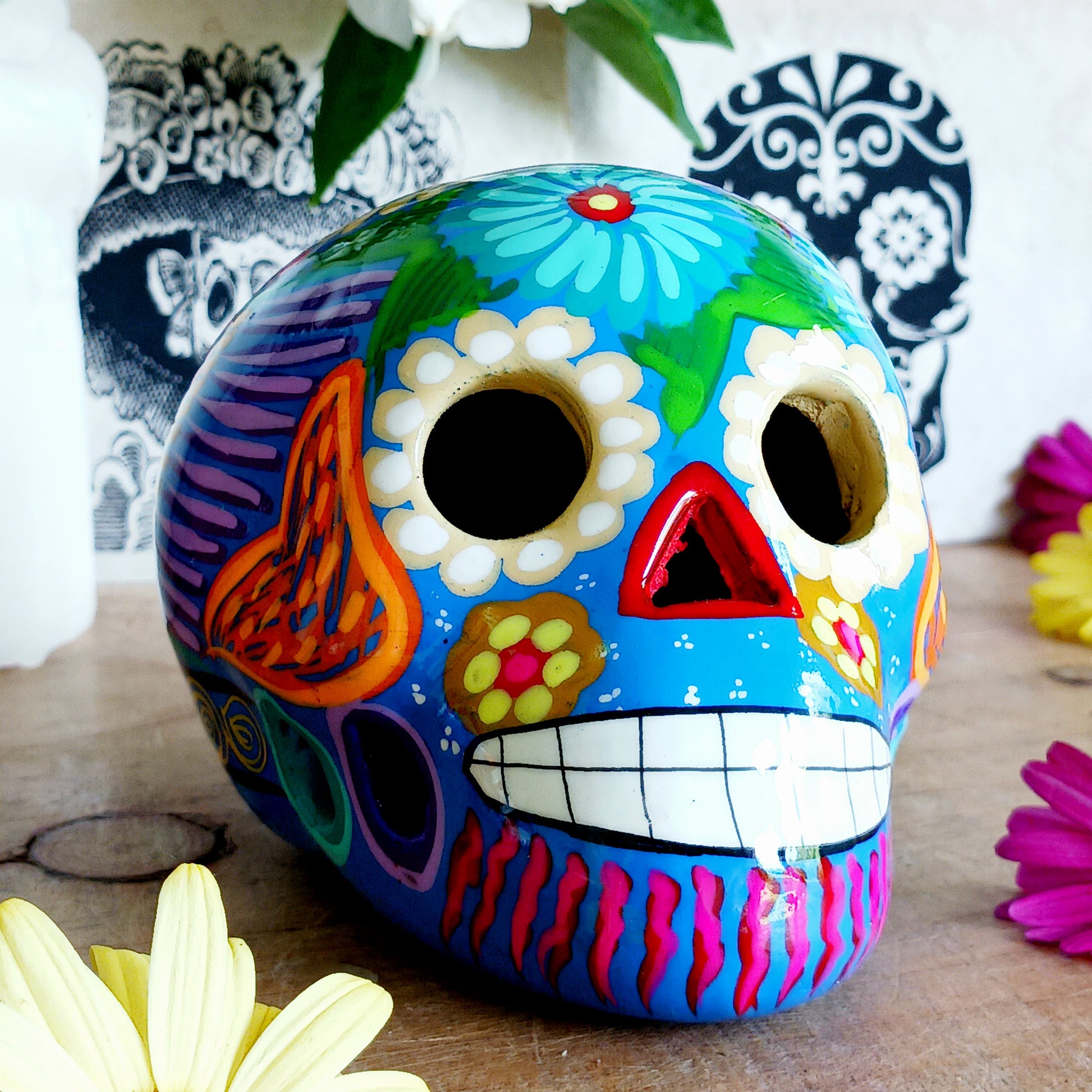 These fun ceramic sugar skull ornaments have been beautifully painted in bright colours and finished with a high shine glaze. They are a popular item during Día de Los Muertos or Day of the Dead festivities, held in Mexico every November to celebrate welcoming the souls of their deceased relatives back for a time of food, drink and celebration.