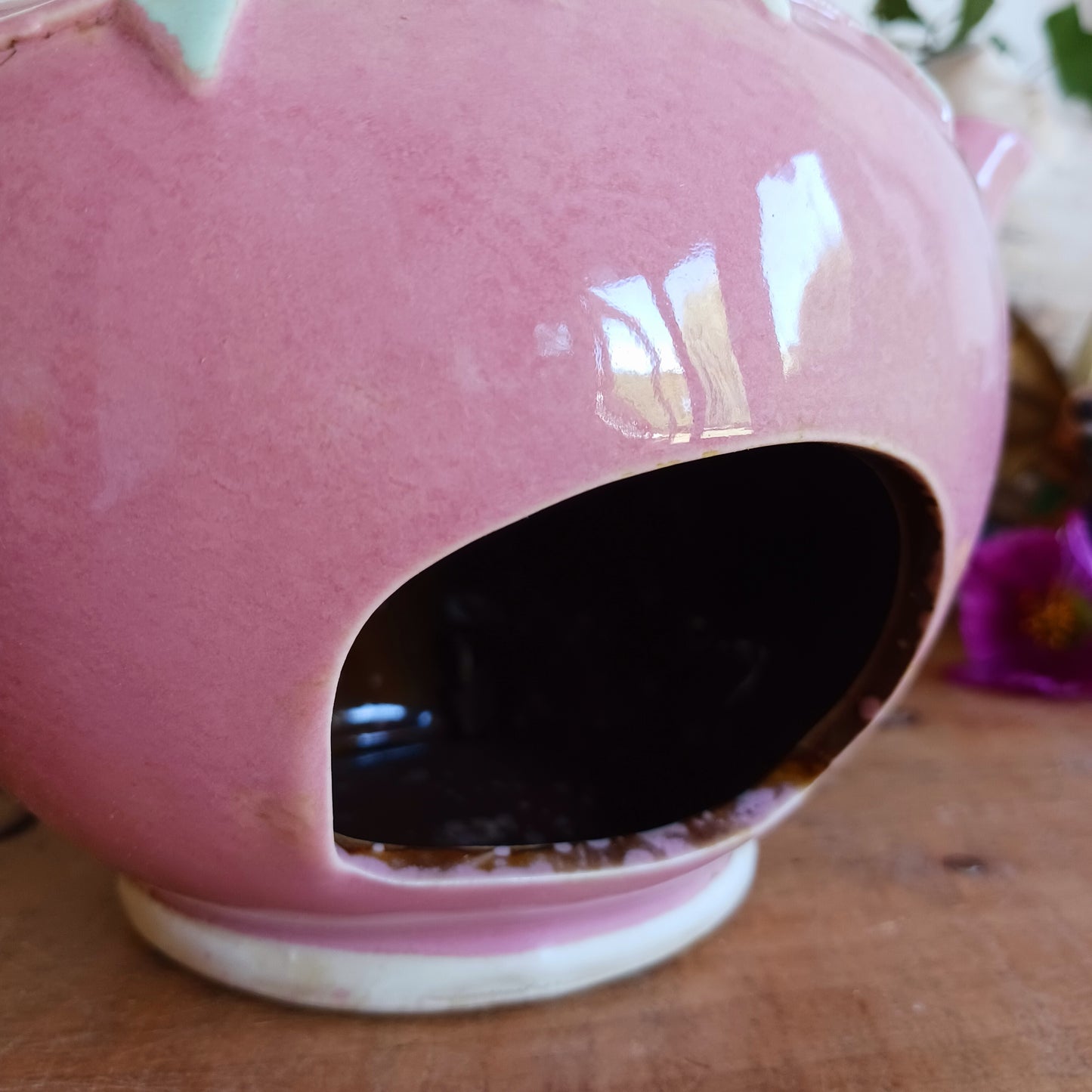 Add a sprinkle of charm to your home with this adorable Village Pottery ceramic tealight holder, beautifully designed as a whimsical pink teapot transformed into a cosy village tea shop. Featuring cottage-style windows, colourful bunting, pretty floral details and a welcoming heart-shaped doorway, this delightful decorative piece brings a touch of storybook magic to any room.