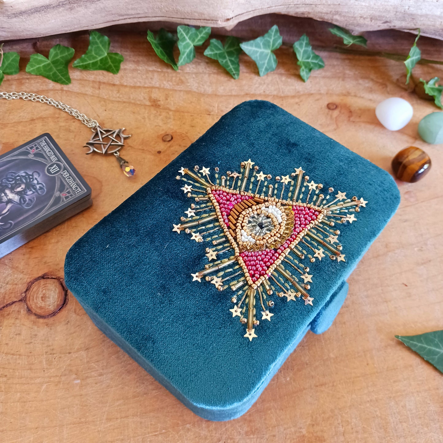 Add elegance and mystique to your collection with this finely embroidered jewellery and tarot box. Made in India and crafted from soft velvet in a rich blue hue, this piece is adorned with intricate embroidery and ornamental beads for a touch of luxury. Perfect for storing jewellery, tarot cards, crystals, or other cherished items, its small strap and button closure keep your treasures secure.