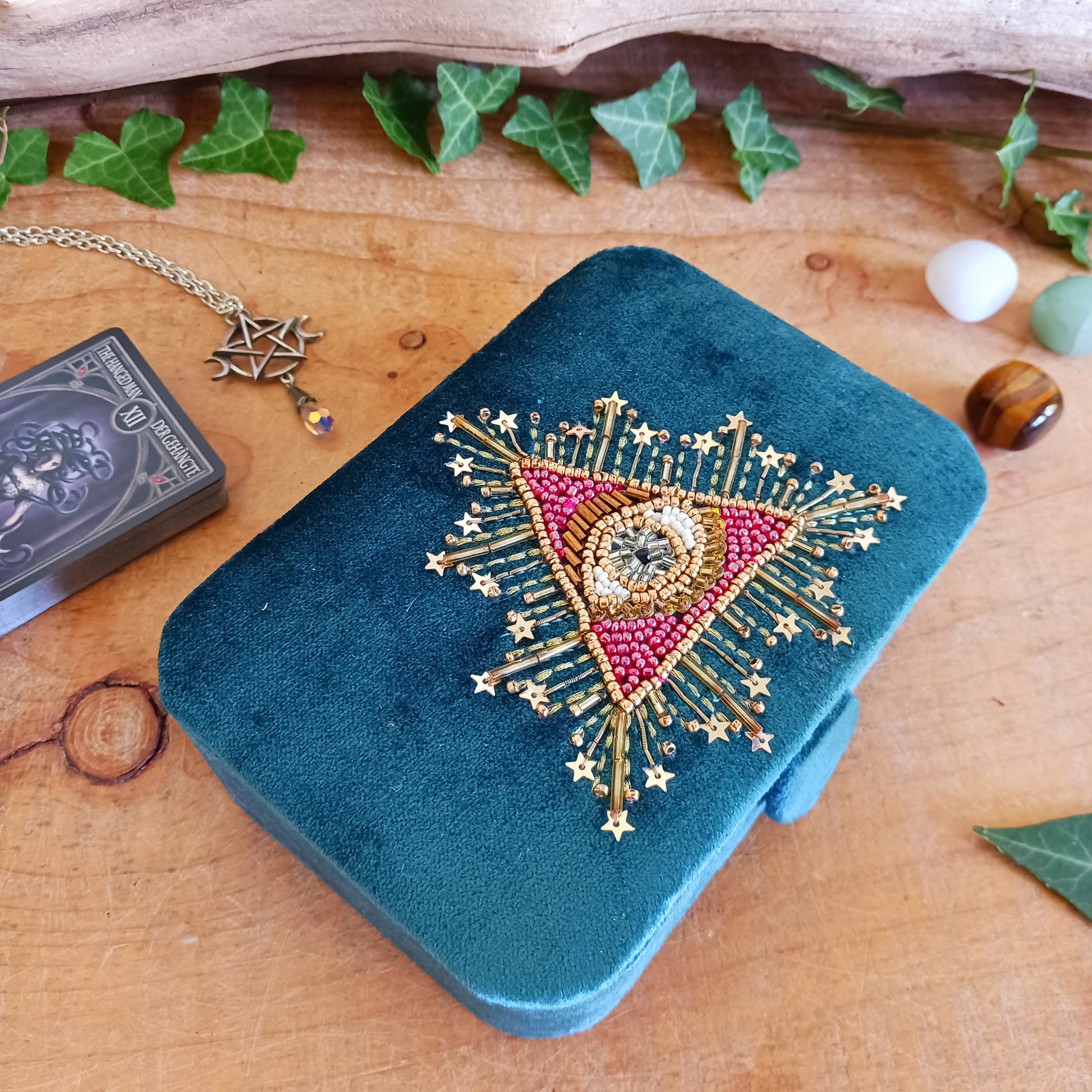 Add elegance and mystique to your collection with this finely embroidered jewellery and tarot box. Made in India and crafted from soft velvet in a rich blue hue, this piece is adorned with intricate embroidery and ornamental beads for a touch of luxury. Perfect for storing jewellery, tarot cards, crystals, or other cherished items, its small strap and button closure keep your treasures secure.