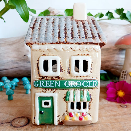 Illuminate your home with the charming Village Pottery Green Grocers Shop Tealight Holder. Handcrafted with a rustic green finish, this cosy piece adds warmth and ambience to any room. Perfect for tealights or simply as a decorative ornament, it’s a delightful addition to shelves, windowsills, or coffee tables. Pair with other pieces from the Village Pottery Collection to create your own quaint, decorative village.