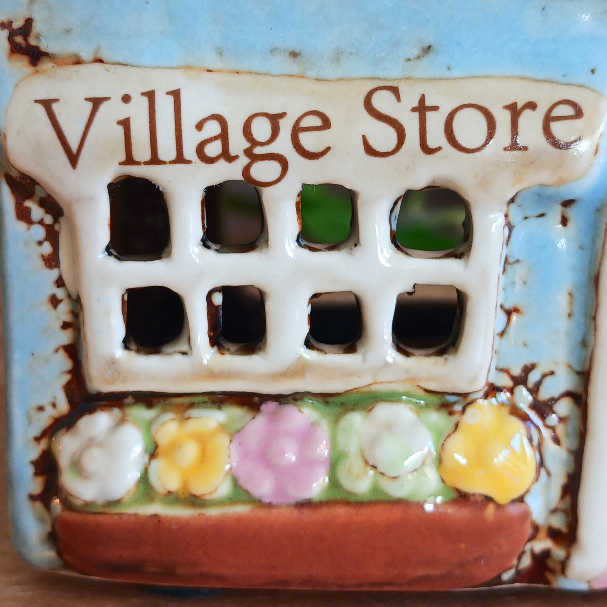 Welcome a touch of storybook charm into your home with the Village Pottery Village Stores Tealight Holder, a handcrafted ceramic delight glowing with the warmth of simpler times. Measuring 15.5 x 9.5 x 8 cm, this quaint miniature shop captures the heart of an old-fashioned village, complete with detailed windows, rustic roof tiles, and painted signage that evokes cosy nostalgia.