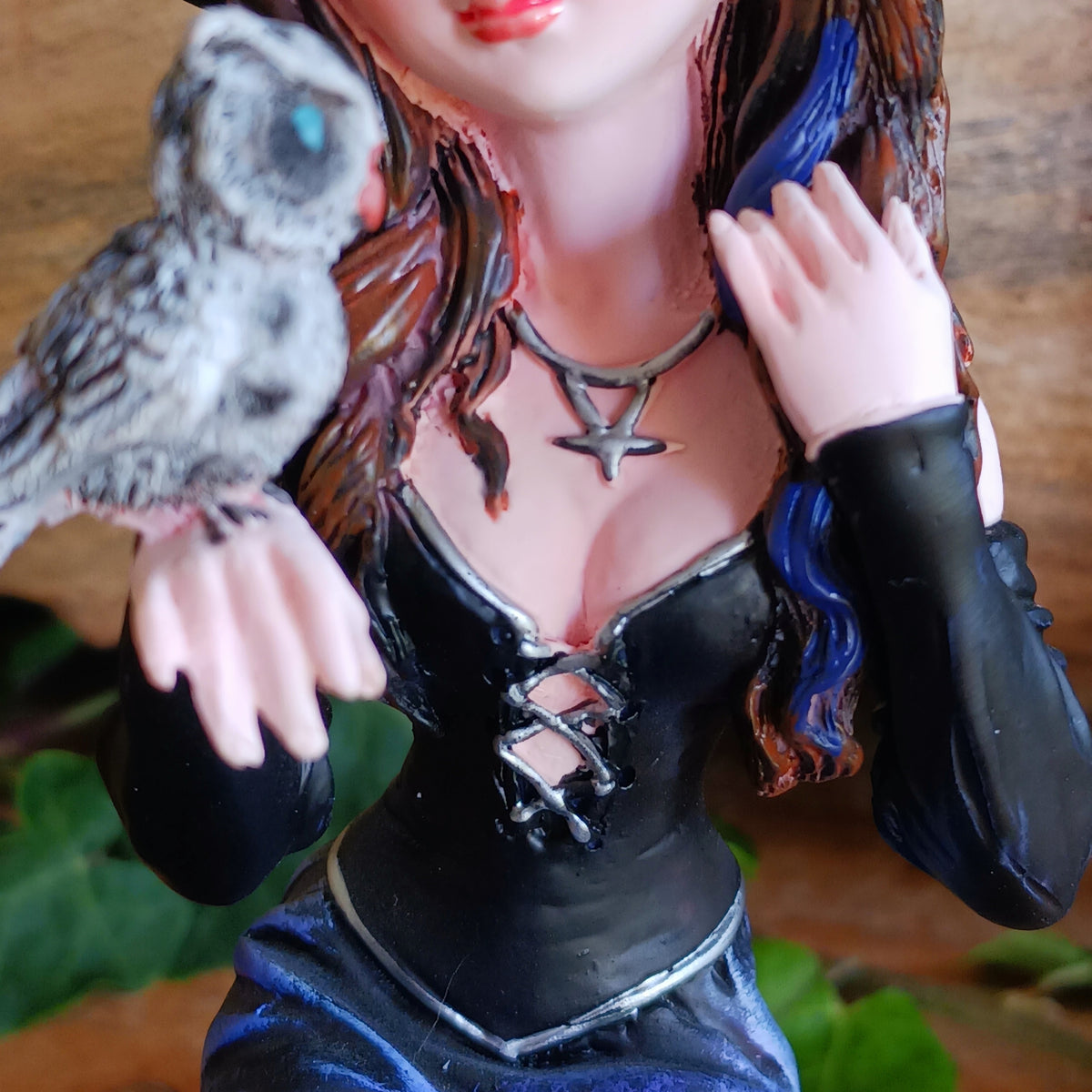 Meet Alvina, a captivating hand-painted witch figurine seated peacefully on a rustic log with her enchanting owl companion. Dressed in a flowing blue gown with long brown hair, Alvina has a mysterious yet charming presence that will appeal to lovers of witches, fantasy and magical décor.