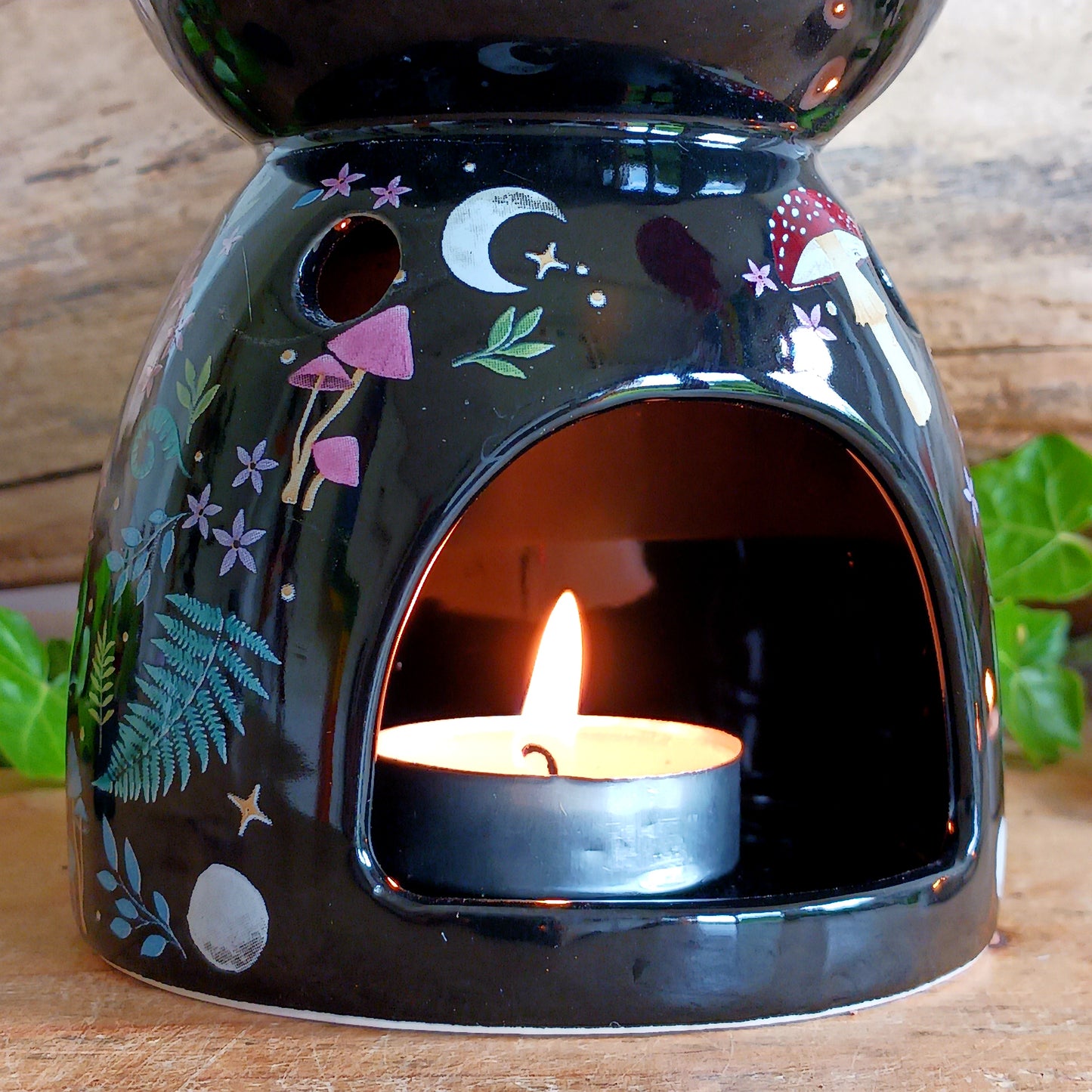 Transform your space into a magical woodland retreat with this beautifully designed dark forest oil burner. Featuring a rich black finish adorned with vibrant illustrations of flora and fauna, this enchanting piece comes to life when lit, casting a warm, ambient glow reminiscent of moonlit nights beneath the stars.