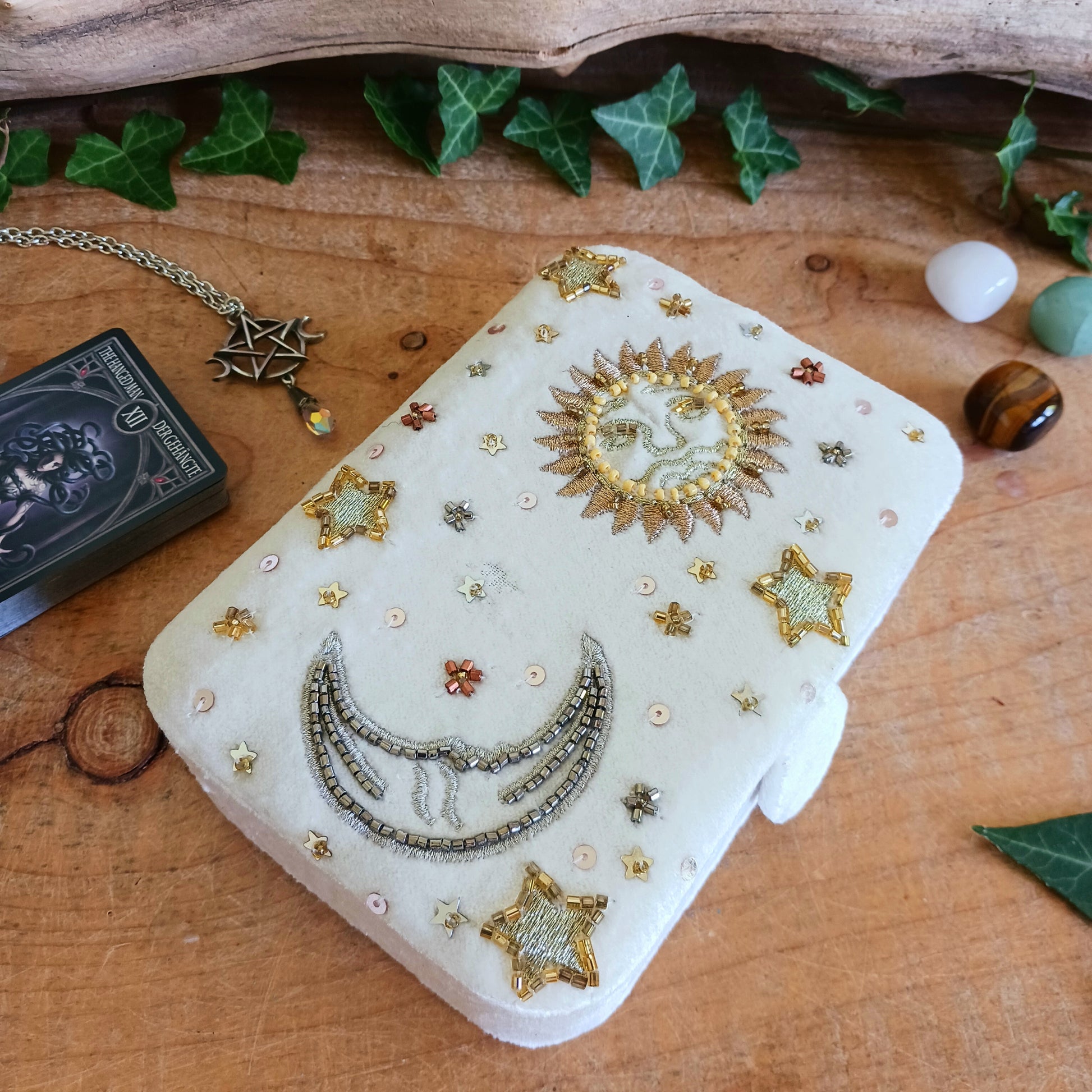 Add elegance and mystique to your collection with this finely embroidered jewellery and tarot box. Made in India and crafted from soft velvet in white, this piece is adorned with intricate embroidery and golden ornamental beads for a touch of luxury. Perfect for storing jewellery, tarot cards, crystals, or other cherished items, its small strap and button closure keep your treasures secure.