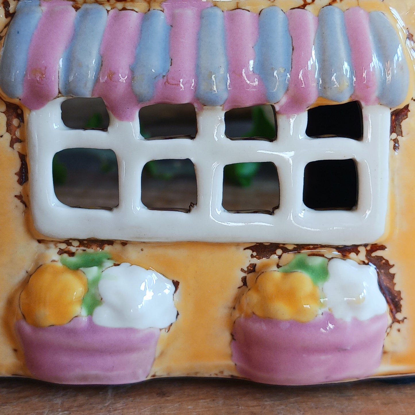 Add a whimsical touch to your décor with the Cards &amp; Gifts Tealight Holder from the Village Pottery Collection. Inspired by the charm of a cozy card shop in a quaint village, this ceramic piece features intricate detailing, from its bunting roof to its delicate windows. Perfect as a tealight holder or simply as a decorative ornament, it brings warmth and character to any space.