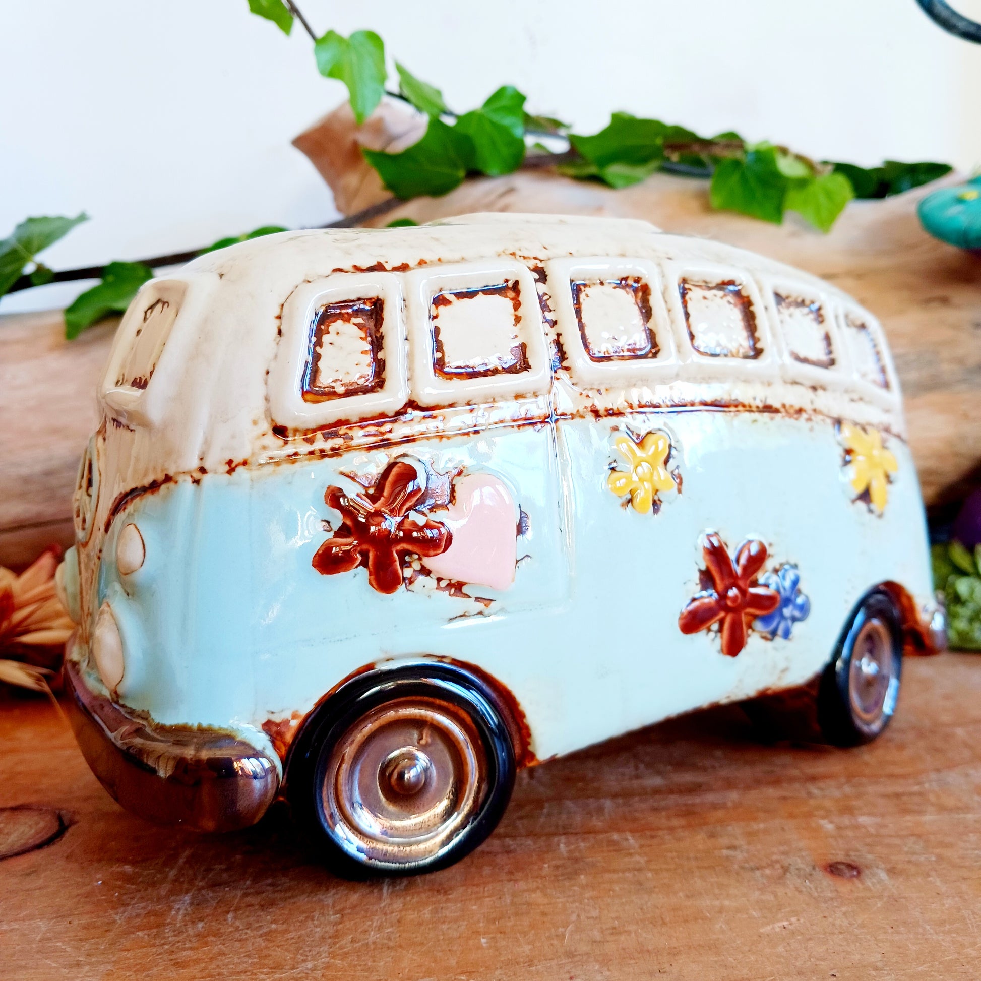From the enchanted lanes of Village Pottery comes this Aqua VW Campervan Money Box, a charming ceramic treasure crafted for dreamers and wanderers alike. Measuring 11 x 18.5 x 10cm, this delightful piece captures the spirit of adventure with its soft aqua glaze, vintage VW Campervan design, and hand-painted detailing that feels kissed by fairy dust.