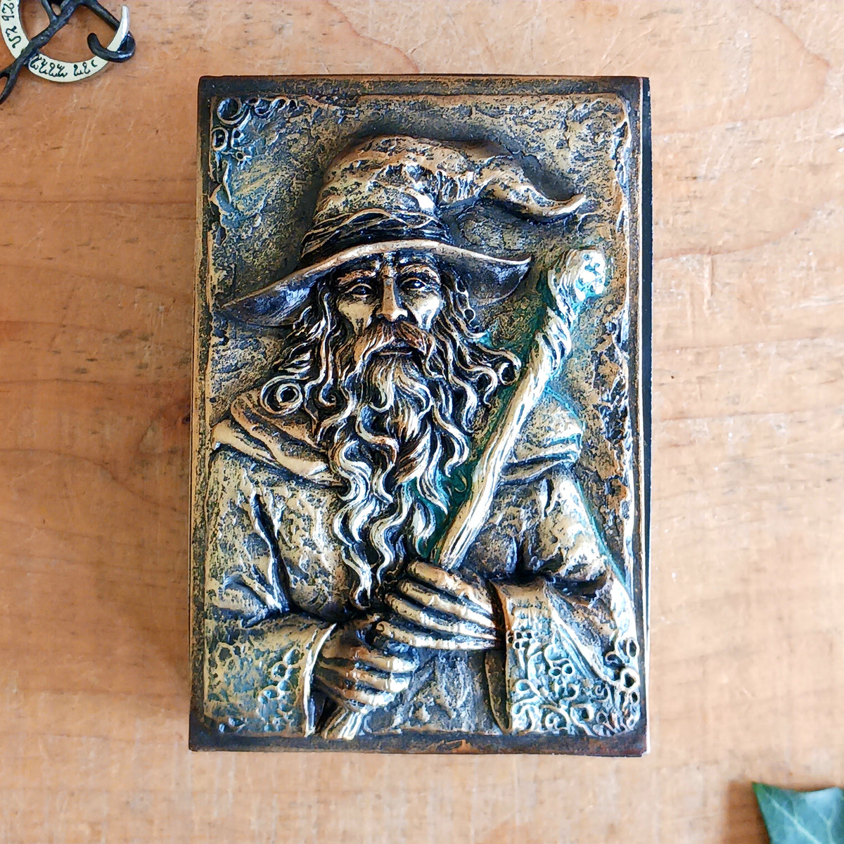 Bring a little magic and mystery into your home with the enchanting Wizard’s Hoard Box. Featuring a beautifully sculpted wizard clutching a magical staff, this decorative trinket box is surrounded by intricate mystical detailing and finished in a rich, antique gold-like colour.