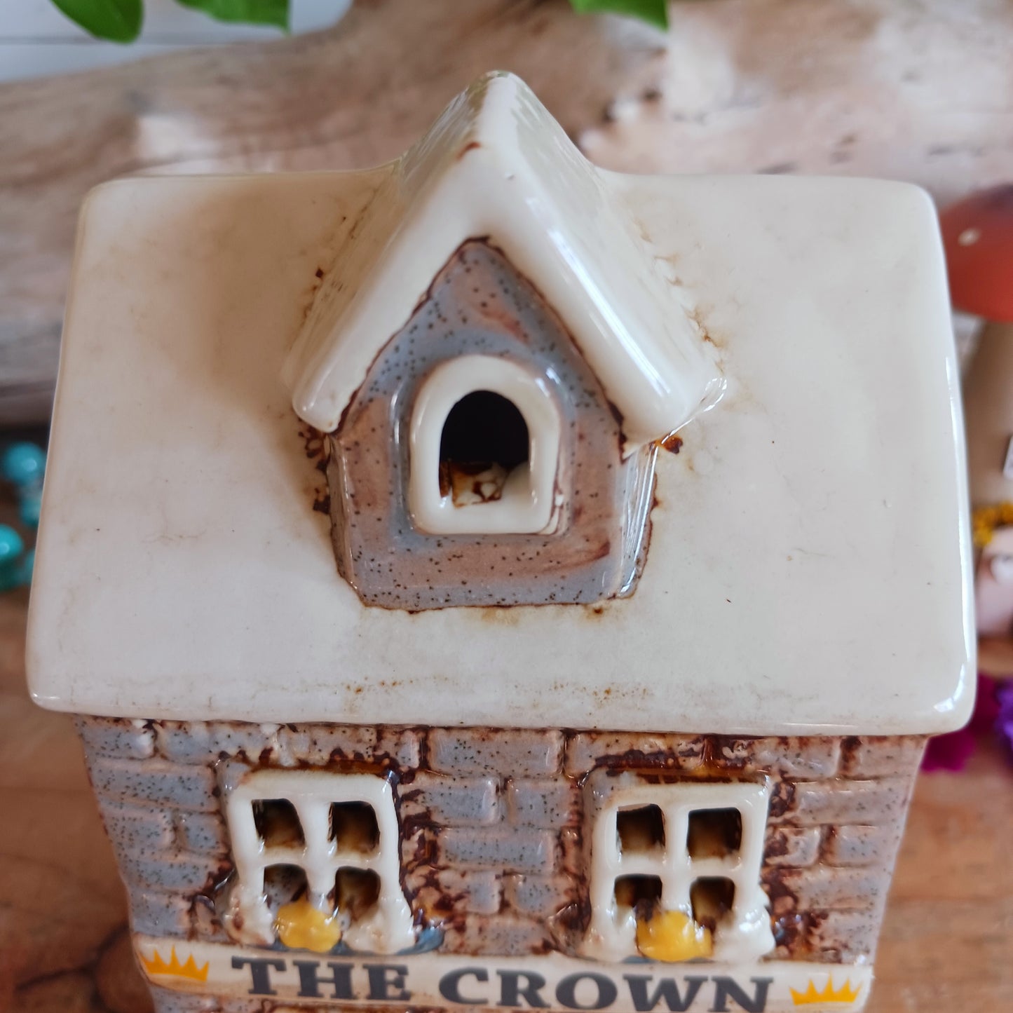 Bring the warmth of a cozy pub into your home with the Village Pottery Crown Pub Tealight. Crafted from ceramic with intricate detailing, this charming piece features a rear cut-out for easy placement of a tealight or string lights. Watch as the soft glow spills through the windows, creating a welcoming pub atmosphere. Perfect for building your own enchanting village display, this timeless decoration adds warmth and character to any space.