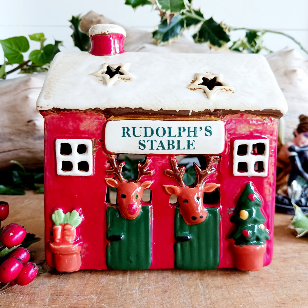 Bring a touch of festive village charm to your home with the Village Pottery Xmas Rudolph’s Stable Tealight Holder. This delightful ceramic Christmas decoration is designed as a quaint little stable, featuring a snowy roof, traditional green doors and charming reindeer detailing.