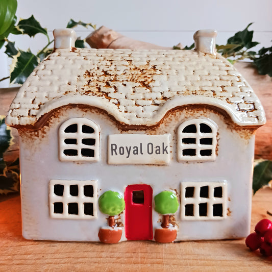 Bring the charm of traditional village life into your home with the Royal Oak Pub Ceramic Tealight Holder. Handcrafted in the Village Pottery workshop, this timeless piece features intricate detailing and rustic finishes inspired by a classic village pub.