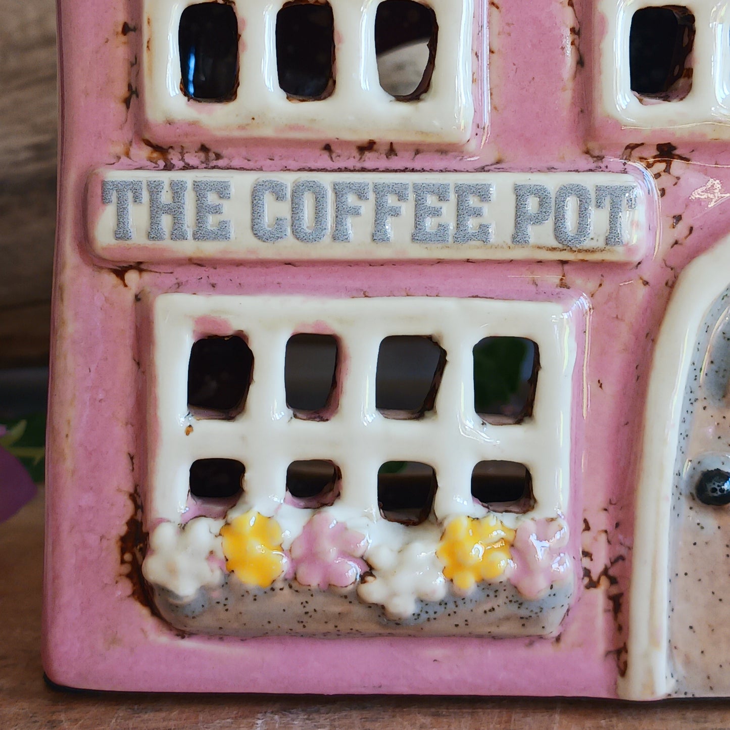 A comforting glow brews within the Coffee Pot Shop, where candlelight flickers like steam rising from a warm cup in a quiet enchanted village. This Shudehill Village Pottery tealight house is crafted from ceramic, casting a soft, golden light through its windows to create a scene of calm and gentle magic.