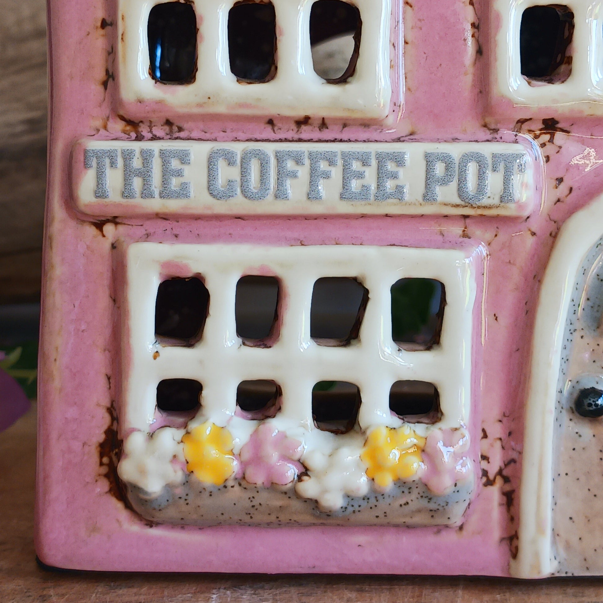 A comforting glow brews within the Coffee Pot Shop, where candlelight flickers like steam rising from a warm cup in a quiet enchanted village. This Shudehill Village Pottery tealight house is crafted from ceramic, casting a soft, golden light through its windows to create a scene of calm and gentle magic.