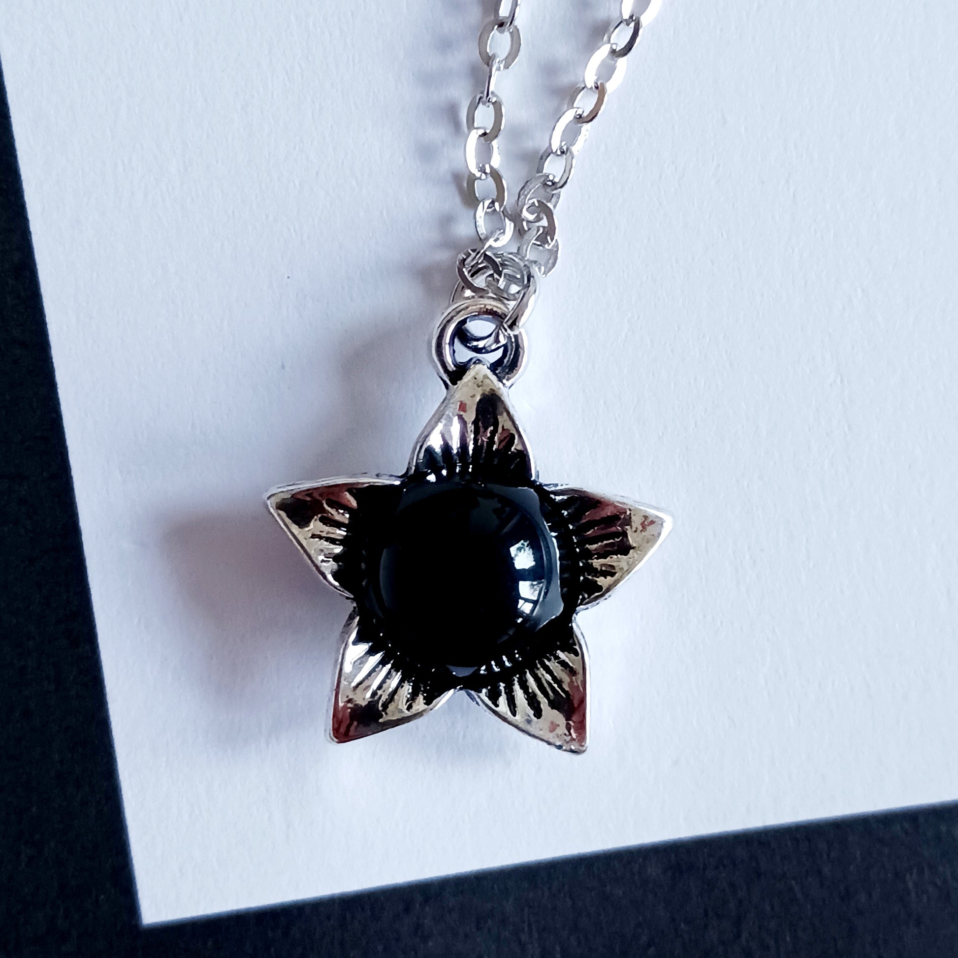 The Deadly Nightshade Necklace with Black Obsidian is a piece of dark elegance, blending nature’s shadowed beauty with gothic symbolism.