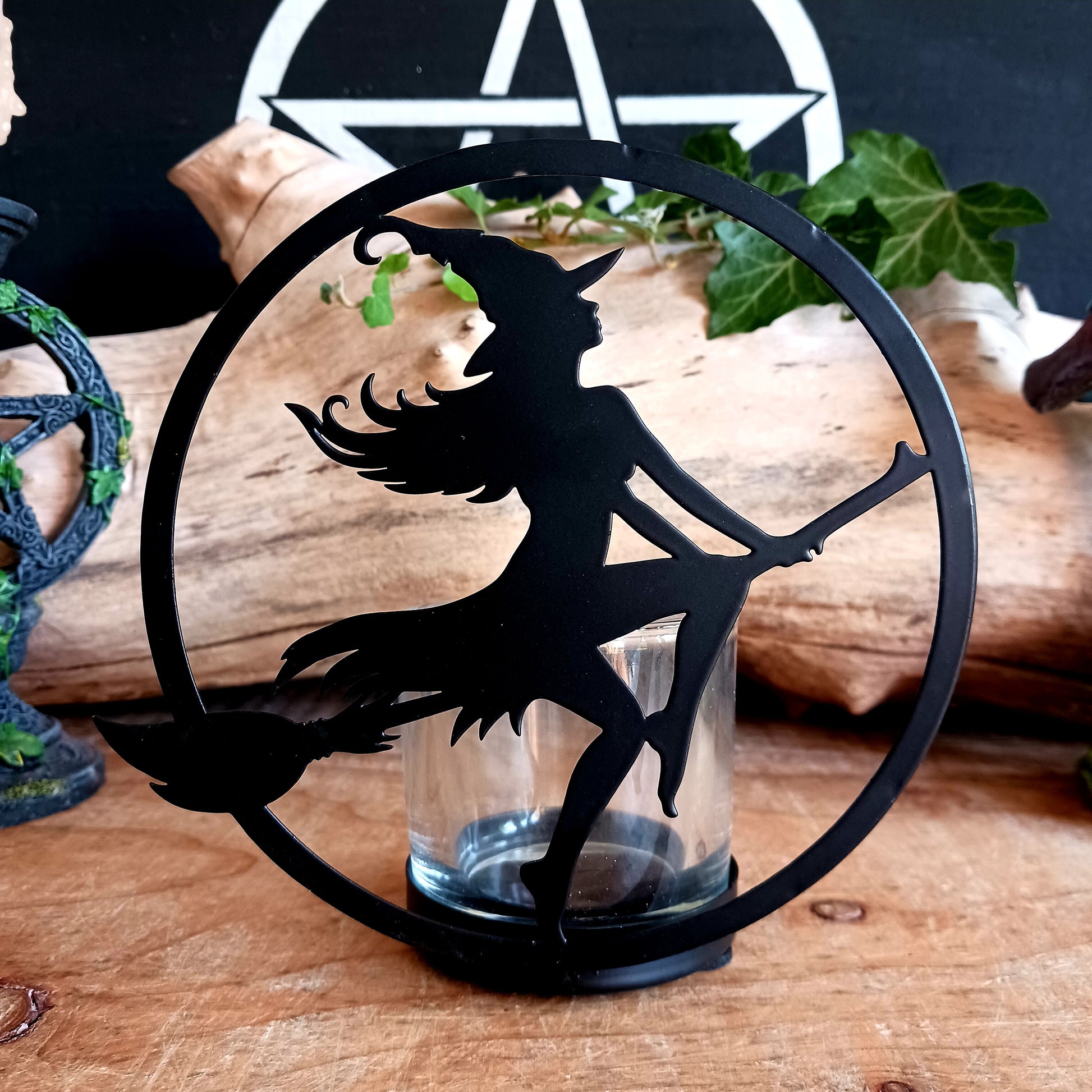 Illuminate your space with the mystical allure of Witch by Moonlight. Crafted from black-coated iron and glass, this enchanting T-light holder depicts the classic silhouette of a witch soaring across a glowing full moon. A tribute to freedom, transformation, and the deep feminine magic within us all, it radiates both mystery and beauty.