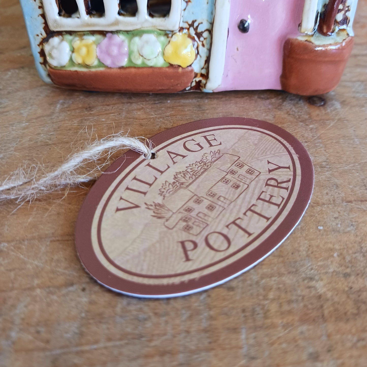 Welcome a touch of storybook charm into your home with the Village Pottery Village Stores Tealight Holder, a handcrafted ceramic delight glowing with the warmth of simpler times. Measuring 15.5 x 9.5 x 8 cm, this quaint miniature shop captures the heart of an old-fashioned village, complete with detailed windows, rustic roof tiles, and painted signage that evokes cosy nostalgia.