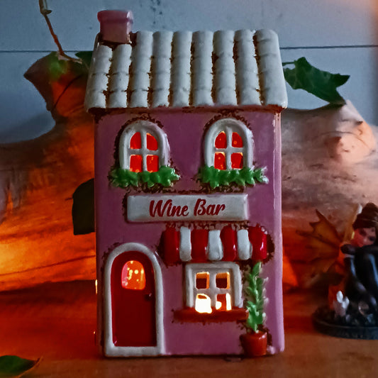 Bring the charm of a quaint village high street into your home with this delightful Village Pottery Wine Bar Tealight Holder. Hand-crafted from ceramic and beautifully hand-painted, this charming miniature wine bar is packed with character and intricate details.