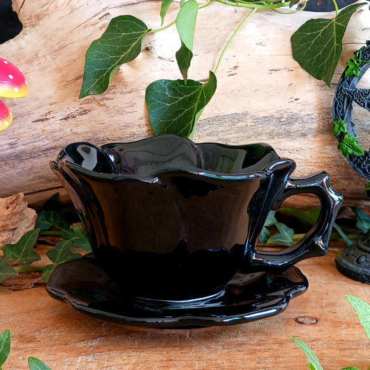 Summon timeless elegance with this black ceramic teacup and matching saucer, sculpted in the likeness of a dark, blooming rose. Designed with a dramatic silhouette and intricate petal detailing, this tea set transforms every sip into a ritual of gothic grace.