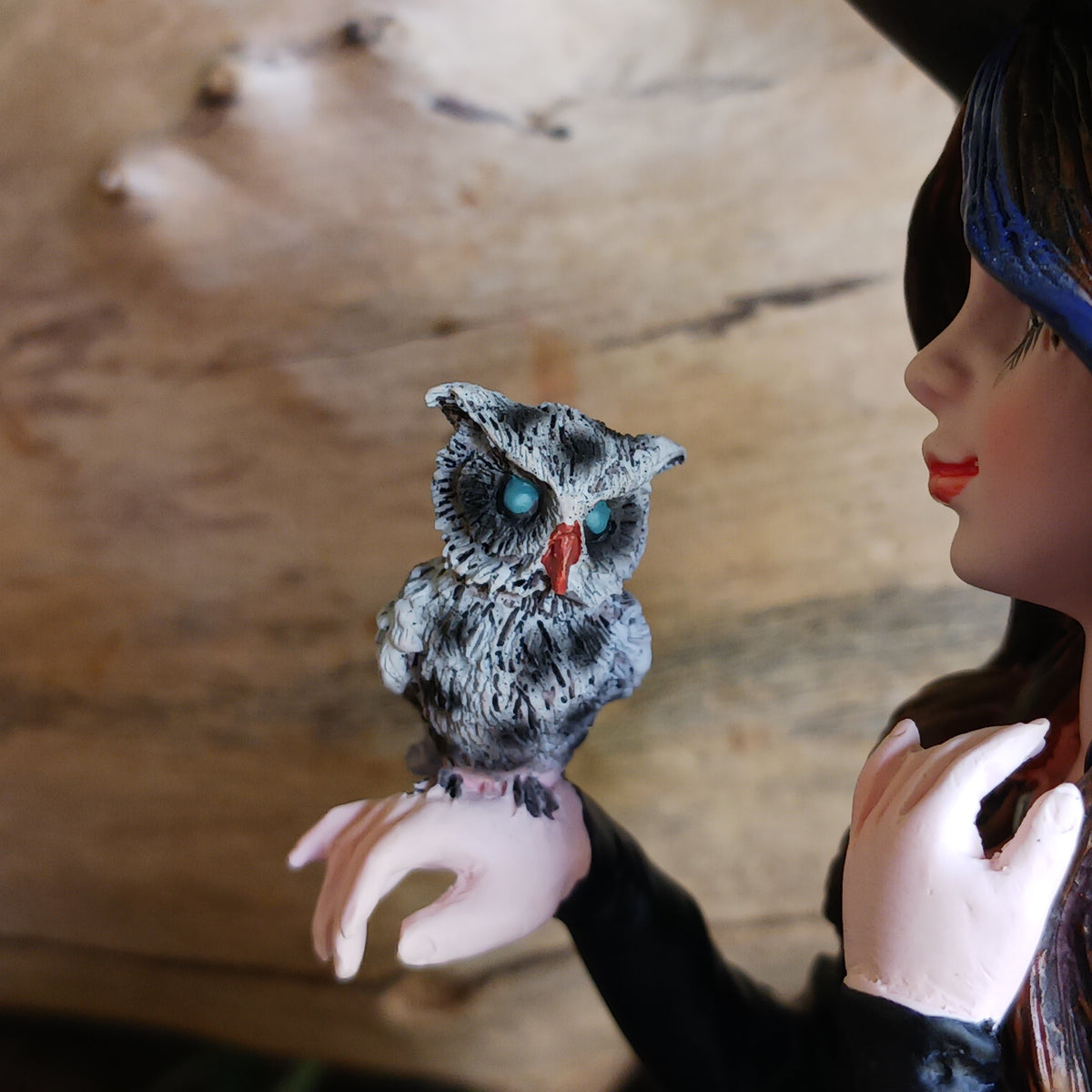 Meet Alvina, a captivating hand-painted witch figurine seated peacefully on a rustic log with her enchanting owl companion. Dressed in a flowing blue gown with long brown hair, Alvina has a mysterious yet charming presence that will appeal to lovers of witches, fantasy and magical décor.