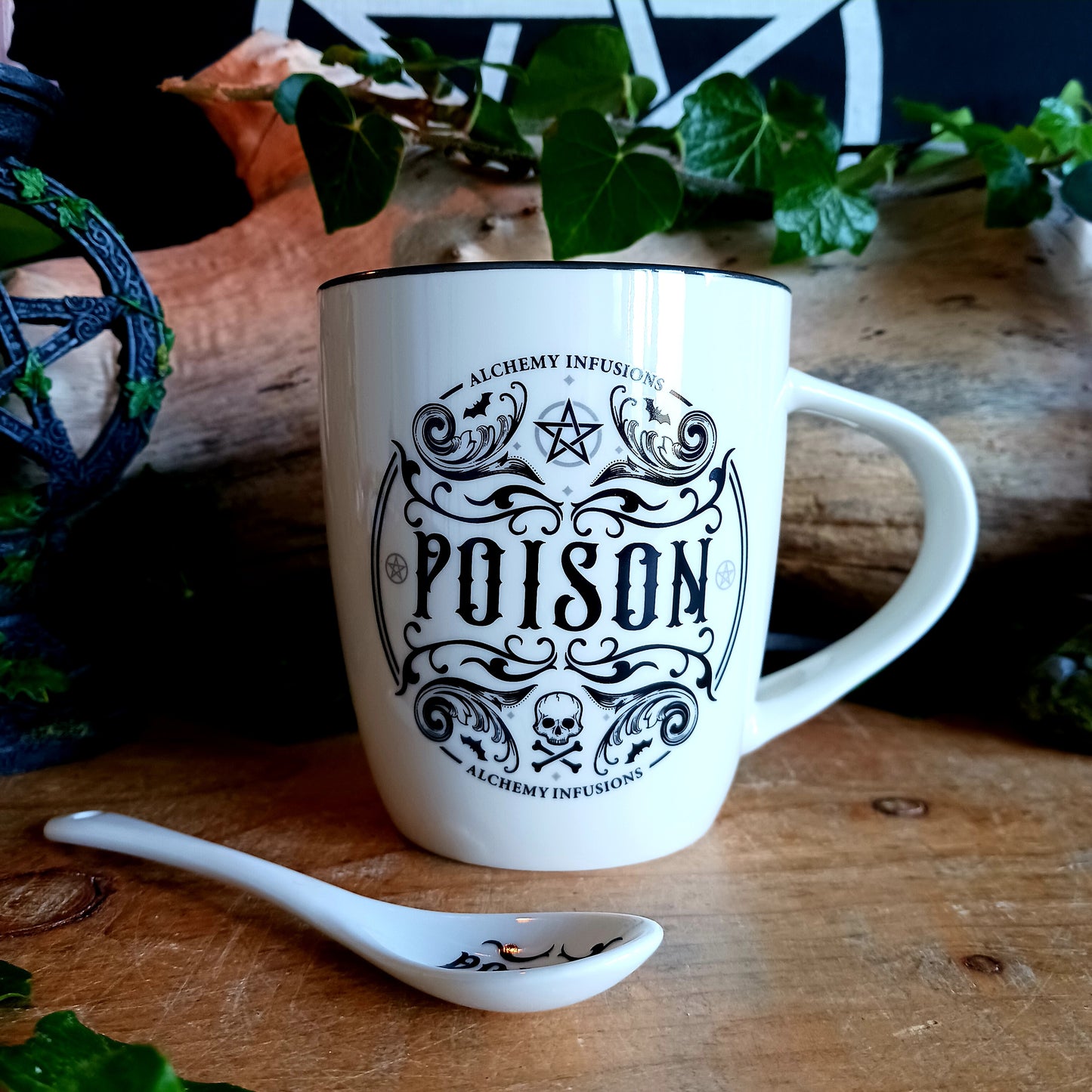 The Poison Mug &amp; Spoon Set by Alchemy is crafted for those who know that beauty can deceive and danger can delight. Made from fine white bone china, this striking mug features intricate Alchemy artwork rich with symbolism — skull and crossbones, pentagrams, tiny bats, and ornate swirling patterns that whisper of alchemy, temptation, and forbidden power.
