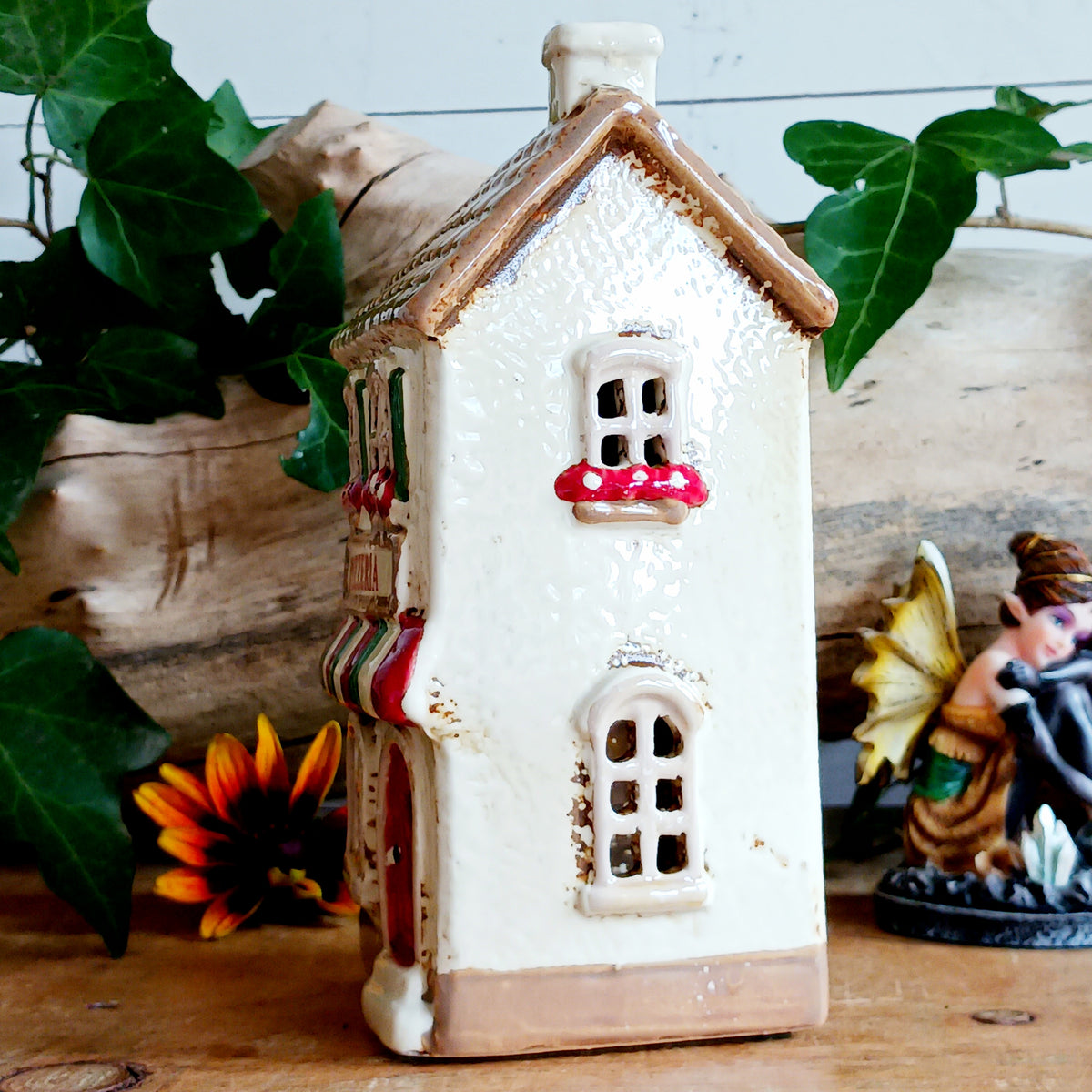Bring a little taste of Italy into your home with this charming Village Pottery Pizzeria Tealight Holder. Designed as a delightful two-storey Italian village building, this cream pottery house features a brown tiled roof, chimney, green shutters, red flower boxes and colourful red and green striped awnings.