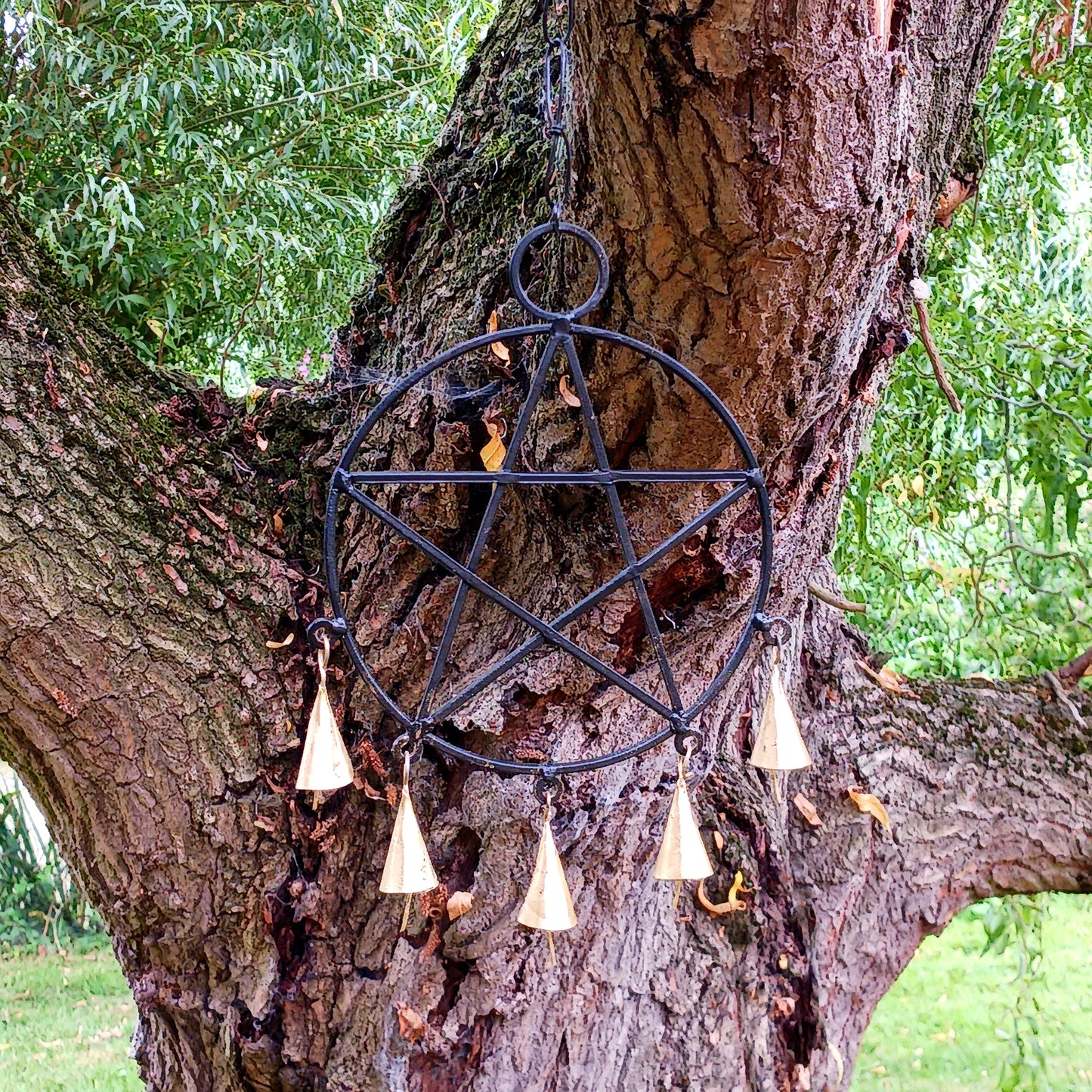 Bring mystical charm and a touch of gothic elegance to your space with this striking black metal pentagram decoration. Crafted with intricate detail, the five-point star hangs gracefully from a sturdy chain and features five fine brass bells that chime softly with movement. Perfect for pagan, Wiccan, or boho-inspired décor, this piece can be hung indoors or outdoors, adding both beauty and symbolism to your home. Ideal for altars, spiritual spaces, or as a unique wall hanging.