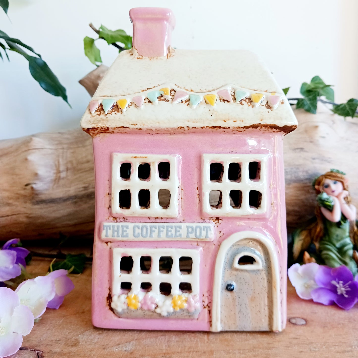 A comforting glow brews within the Coffee Pot Shop, where candlelight flickers like steam rising from a warm cup in a quiet enchanted village. This Shudehill Village Pottery tealight house is crafted from ceramic, casting a soft, golden light through its windows to create a scene of calm and gentle magic.