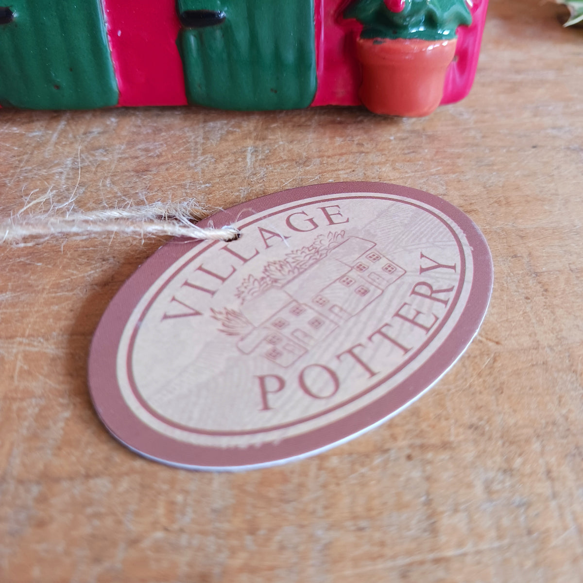 Bring a touch of festive village charm to your home with the Village Pottery Xmas Rudolph’s Stable Tealight Holder. This delightful ceramic Christmas decoration is designed as a quaint little stable, featuring a snowy roof, traditional green doors and charming reindeer detailing.