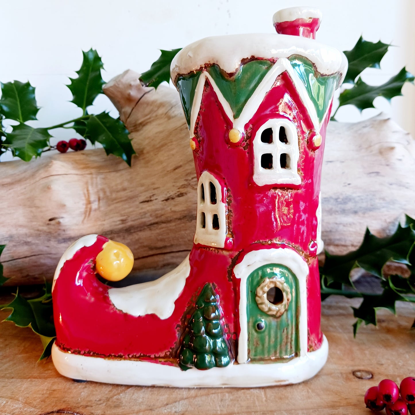 Step into the world of festive enchantment with the Village Pottery Christmas Elf Boot House Tealight Holder, a playful handcrafted ceramic creation bursting with Christmas spirit. Measuring 16 x 16 x 9.5 cm, this delightful piece takes the shape of a cheerful elf’s boot turned into a cosy little house, complete with twinkling windows and snowy details.
