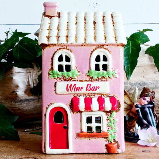 Bring the charm of a quaint village high street into your home with this delightful Village Pottery Wine Bar Tealight Holder. Hand-crafted from ceramic and beautifully hand-painted, this charming miniature wine bar is packed with character and intricate details.