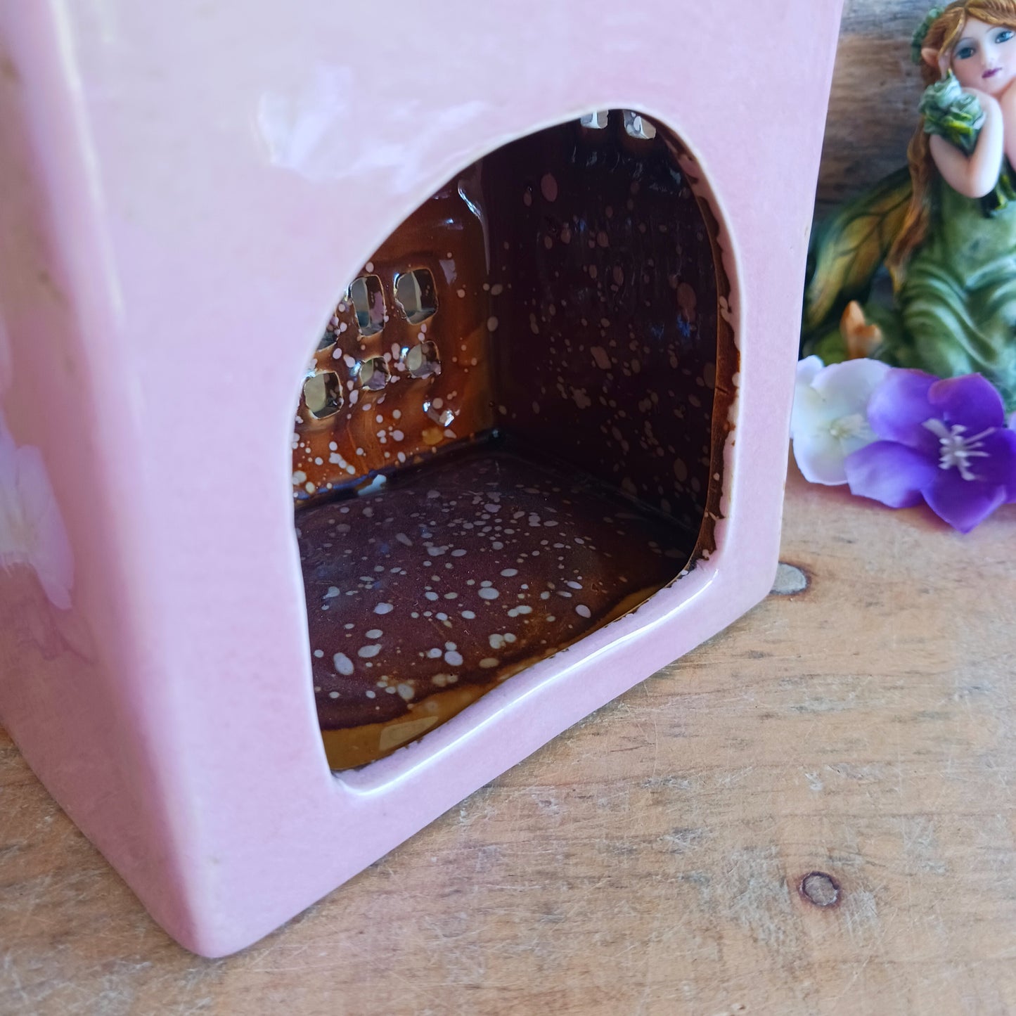 A comforting glow brews within the Coffee Pot Shop, where candlelight flickers like steam rising from a warm cup in a quiet enchanted village. This Shudehill Village Pottery tealight house is crafted from ceramic, casting a soft, golden light through its windows to create a scene of calm and gentle magic.