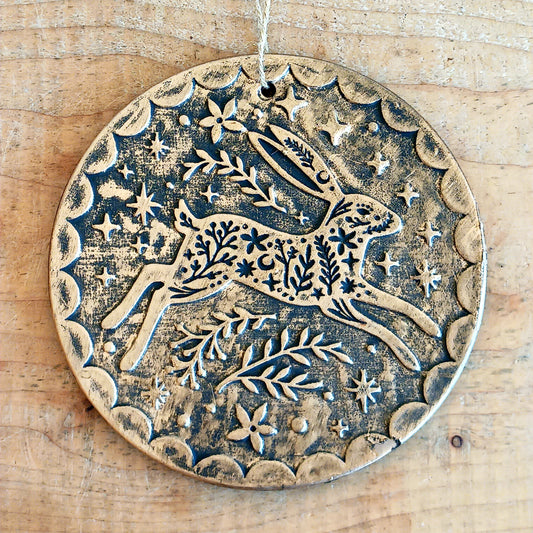 Add a touch of seasonal magic to your home or garden with this enchanting Winter Solstice Hare Hanging Plaque. Crafted from terracotta and finished with an attractive brushed bronze effect, the plaque features an elegant leaping hare surrounded by intricate botanical detailing inspired by the beauty of the natural world.