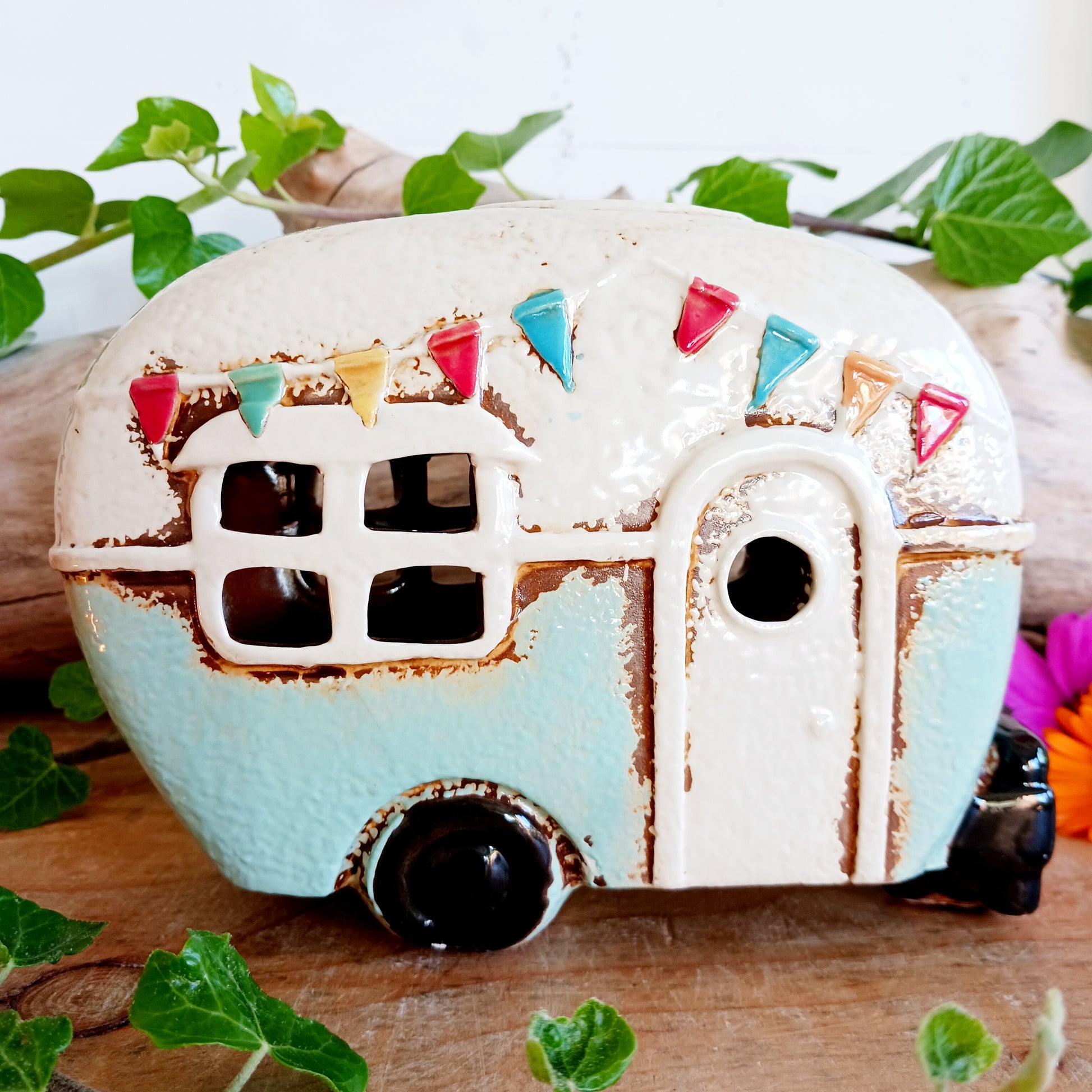 From the enchanted lanes of Village Pottery comes this Aqua Caravan Money Box, a charming ceramic treasure crafted for dreamers and wanderers alike. Measuring 13.5 x 18.5 x 6.5 cm, this delightful piece captures the spirit of adventure with its soft aqua glaze, vintage caravan design, and hand-painted detailing that feels kissed by fairy dust.