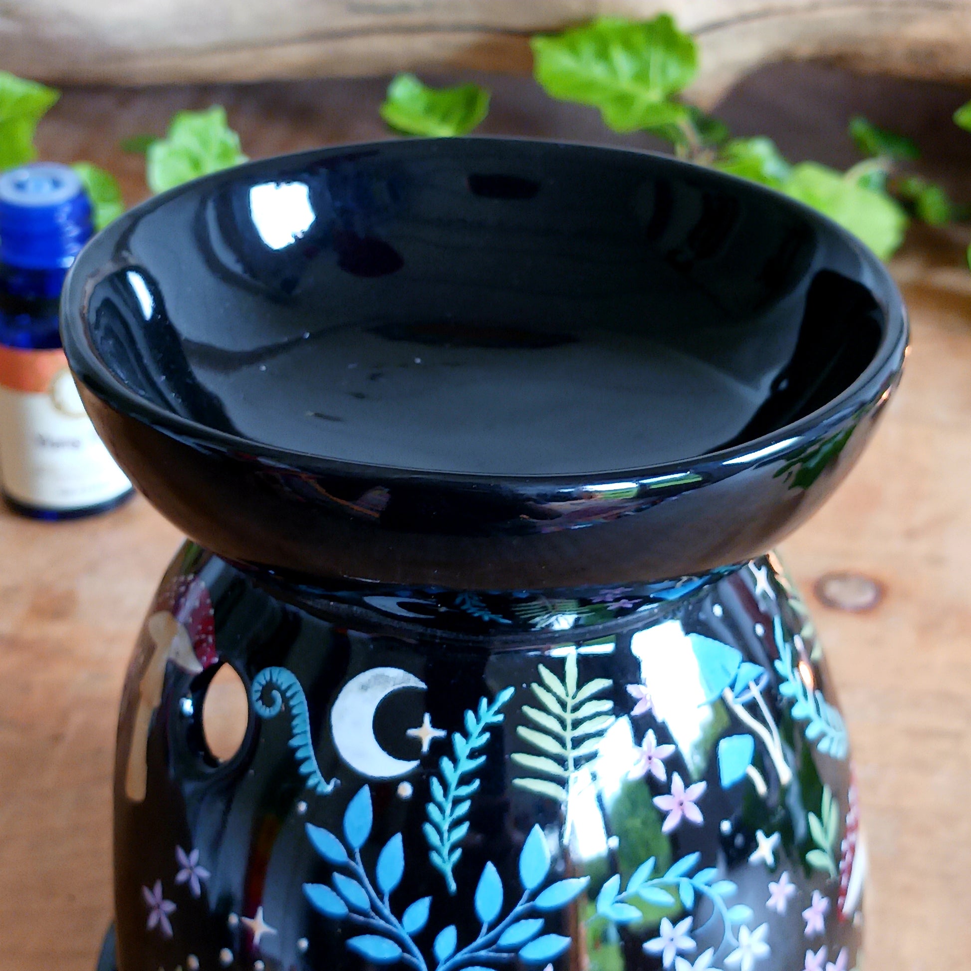 Transform your space into a magical woodland retreat with this beautifully designed dark forest oil burner. Featuring a rich black finish adorned with vibrant illustrations of flora and fauna, this enchanting piece comes to life when lit, casting a warm, ambient glow reminiscent of moonlit nights beneath the stars.