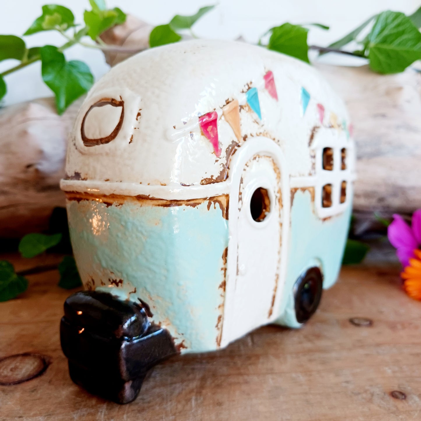 From the enchanted lanes of Village Pottery comes this Aqua Caravan Money Box, a charming ceramic treasure crafted for dreamers and wanderers alike. Measuring 13.5 x 18.5 x 6.5 cm, this delightful piece captures the spirit of adventure with its soft aqua glaze, vintage caravan design, and hand-painted detailing that feels kissed by fairy dust.