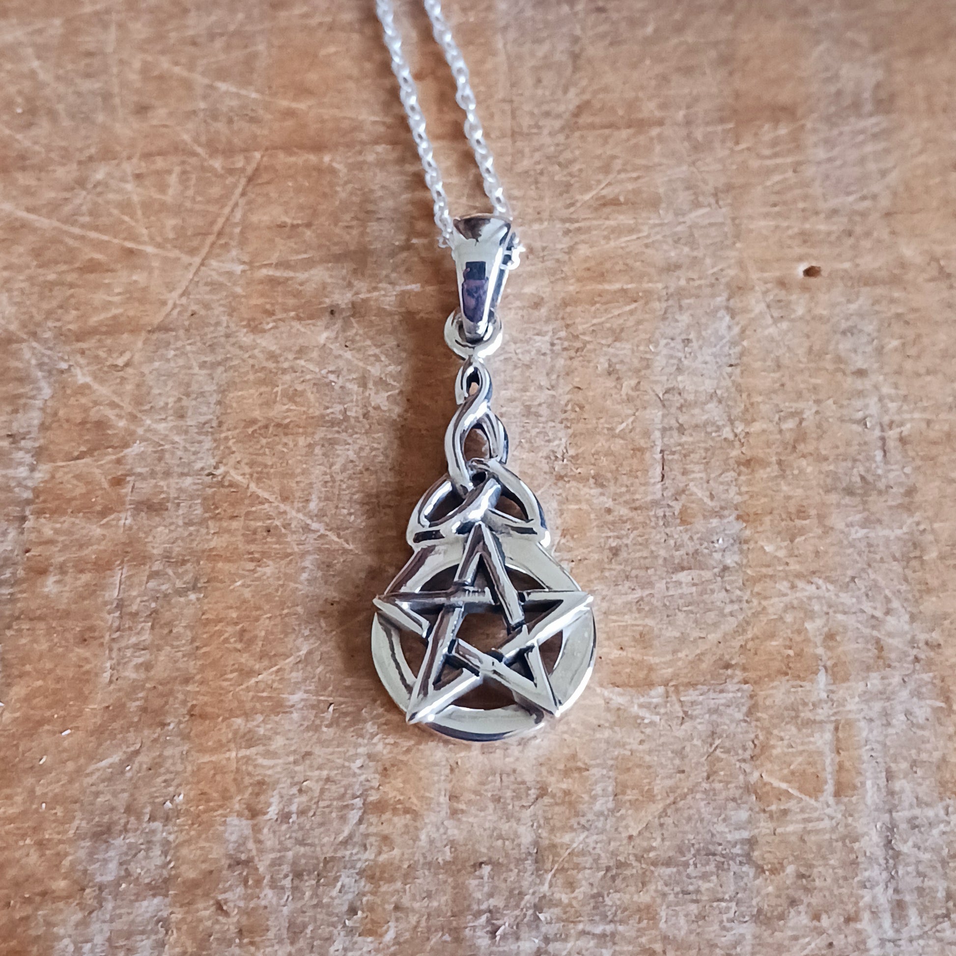 This beautiful pendant creates a significant and luminous amulet. The design is vertically oriented, featuring two distinct but harmoniously linked symbols. At the base is a prominent, circular Five-Pointed Star (Pentacle/Pentagram), the classic symbol of protection and the balanced harmony of the five elements.