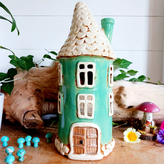 Add warmth and charm to your space with this teal round tealight house. Crafted from quality ceramic, this decorative piece makes a perfect gift or a cozy addition to your own home. Display it as a stand-alone ornament or pop in a tealight to create a soft, inviting glow. For a magical touch, collect the full range and build your own enchanting village of light.