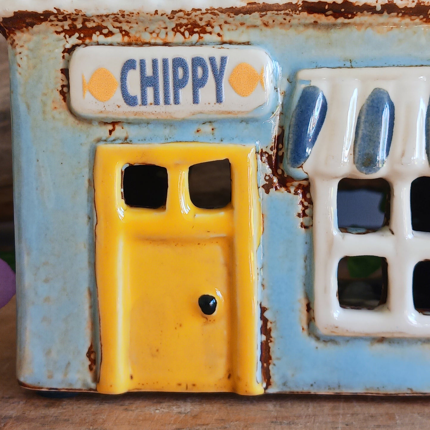 A warm, golden glow spills from the windows of this Village Pottery Chippy, where the spirit of a bustling village meets quiet enchantment. Crafted from ceramic, this Shudehill tealight house captures a familiar yet mystical charm, as candlelight flickers like stories shared after dusk.