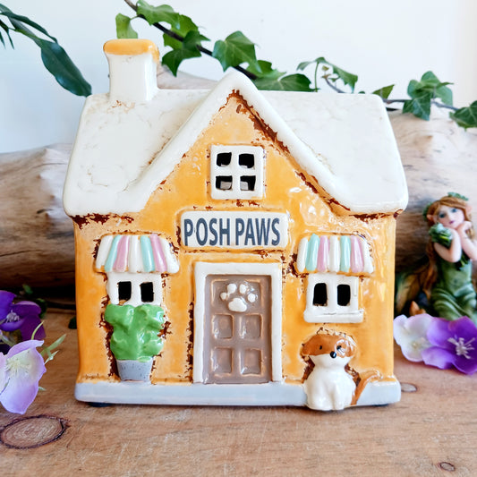 A gentle glow shines from Posh Paws, where tiny windows flicker with warmth as if welcoming beloved companions into a magical village haven. This Shudehill Village Pottery tealight house is crafted from ceramic, allowing candlelight to dance softly through its details, creating a comforting and enchanted atmosphere.