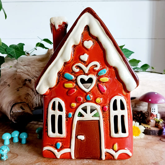 Bring warmth and charm into your home with this beautifully handcrafted ceramic gingerbread house tealight holder by Village Pottery. Each piece is individually crafted and hand-finished, making every house delightfully unique. When lit with a tealight, a cozy glow shines through the windows, creating a magical ambiance. Decorated with candy-inspired details, this tall gingerbread house makes a perfect gift for birthdays, housewarmings, holidays, or as a festive accent in your own space.