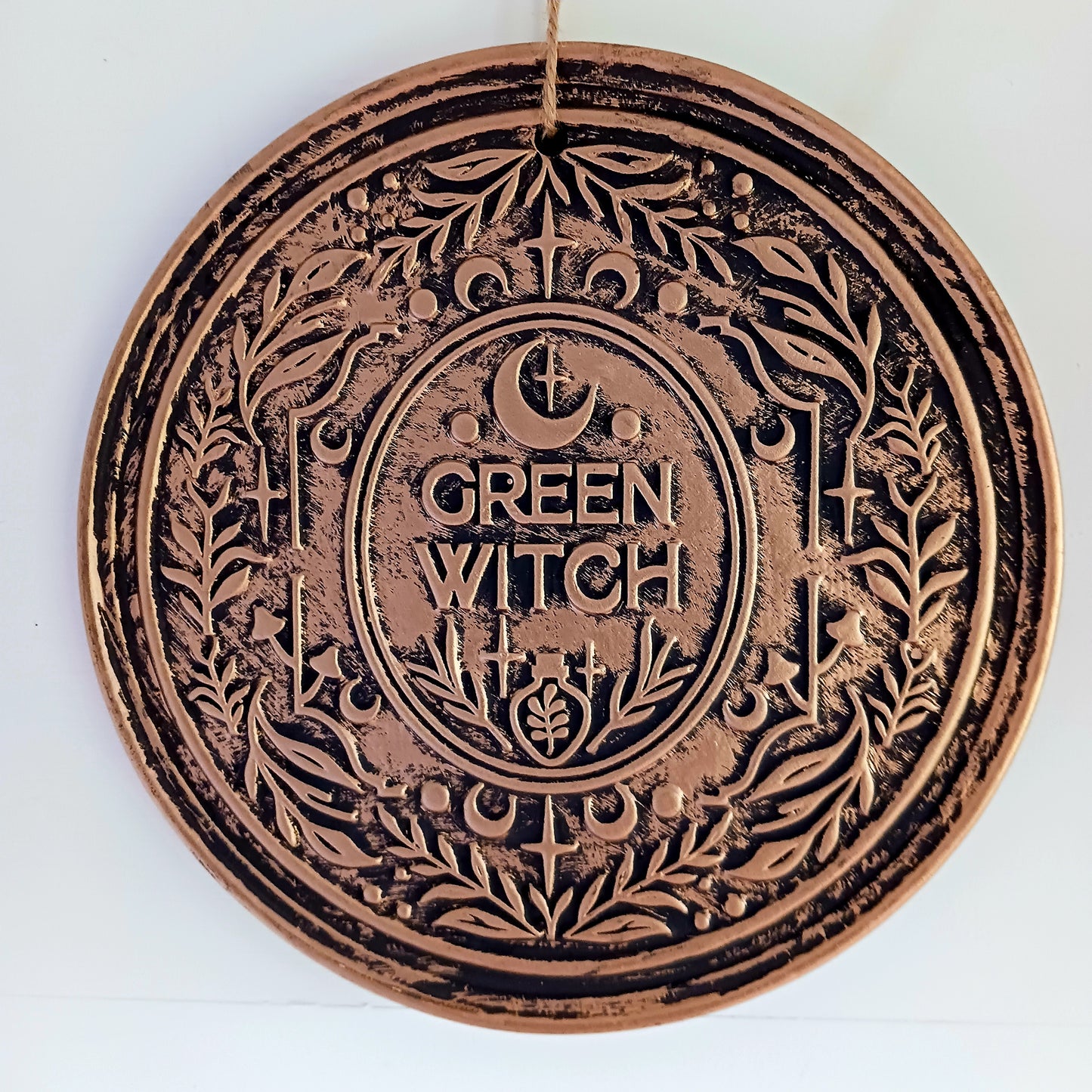The Green Witch Bronze Effect Terracotta Hanging Plaque infuses your space with grounded, earthy energy and ancient symbolism.